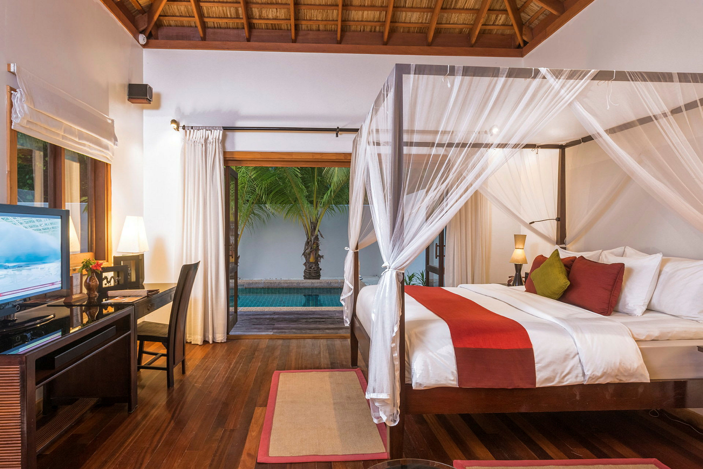 Et værelse med en himmelseng, skrivebord og en åbning ud til en pool og grønne omgivelser udenfor. (AI-genereret tekst)