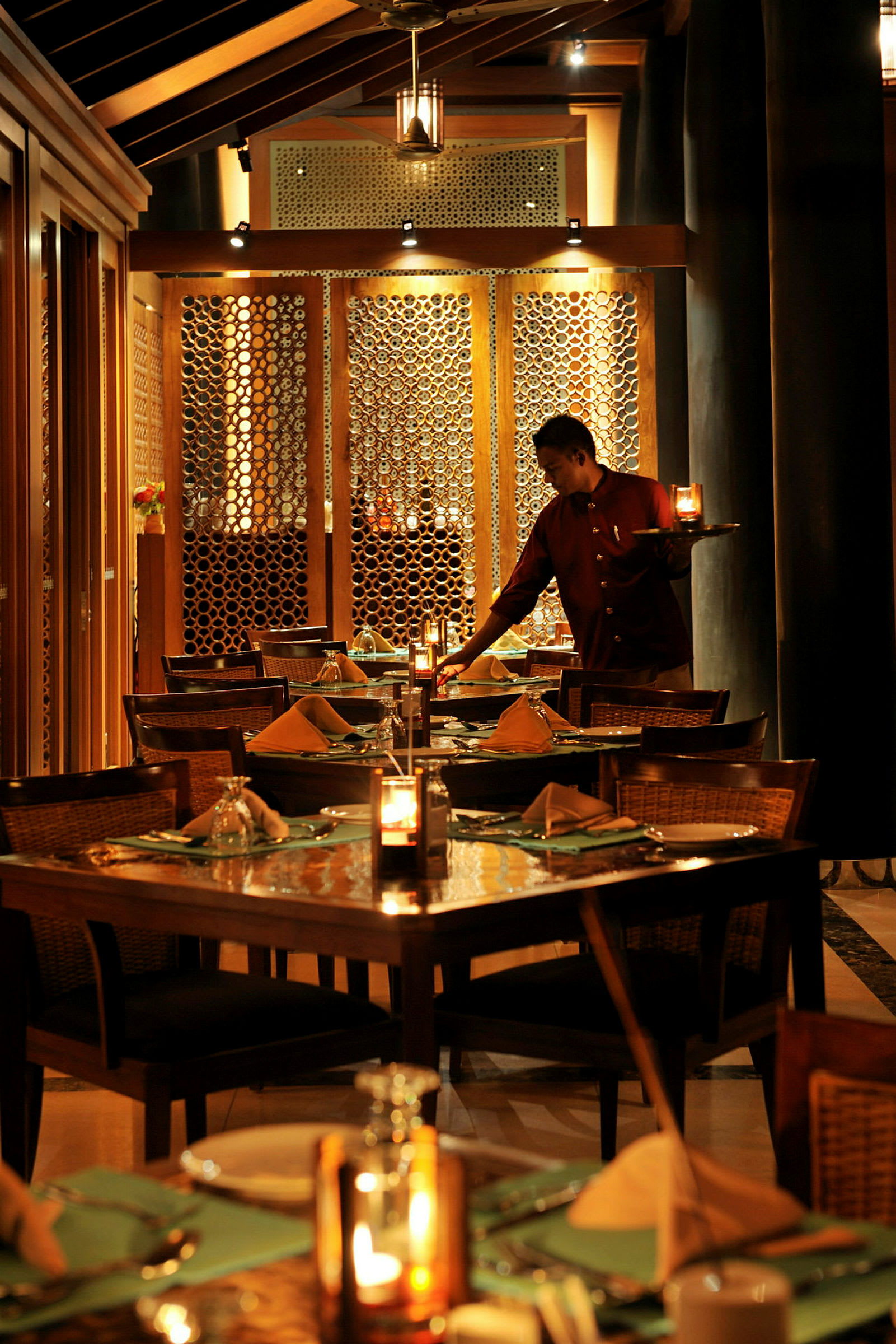 En oplyst restaurant med dækkede borde og en person, der serverer. (AI-genereret tekst)