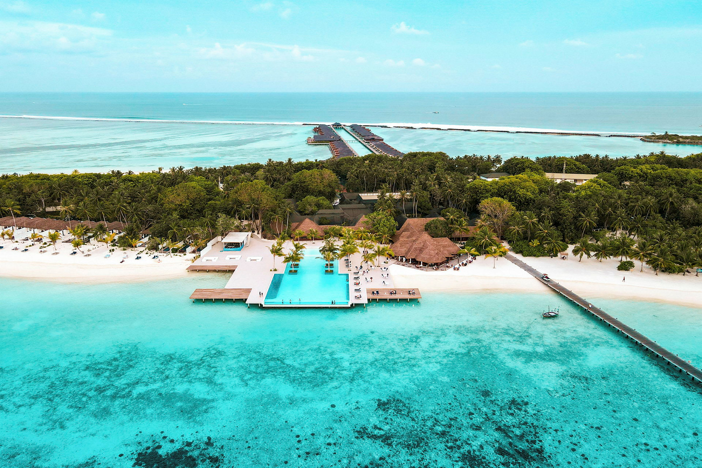 Luftfoto af en tropisk strand med turkis vand, palmer og en infinitypool. (AI-genereret tekst)