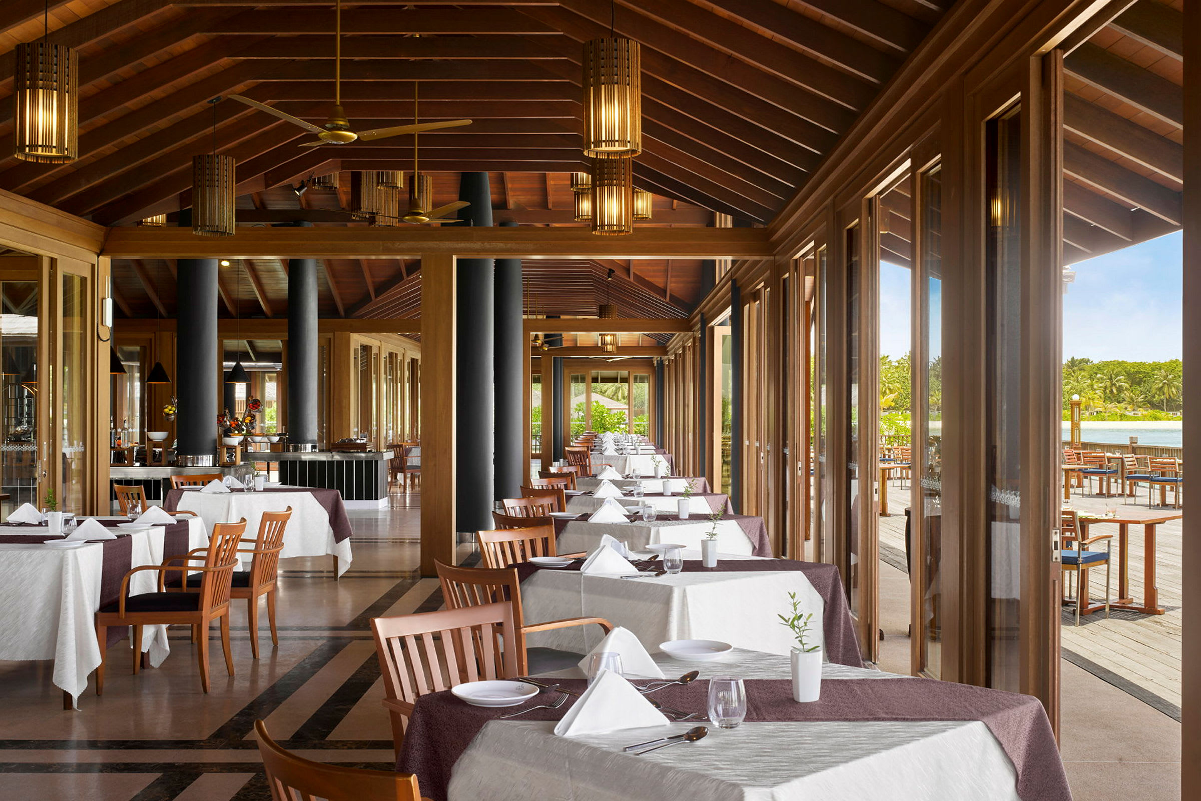 En restaurant med dækkede borde og store vinduer med udsigt til en terrasse. (AI-genereret tekst)