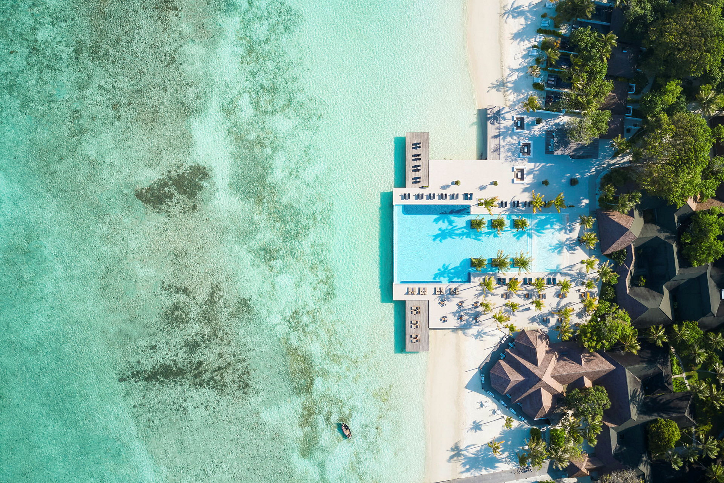 Luftfoto af et luksuriøst strandresort med pool, hvide sandstrande og turkis vand. (AI-genereret tekst)