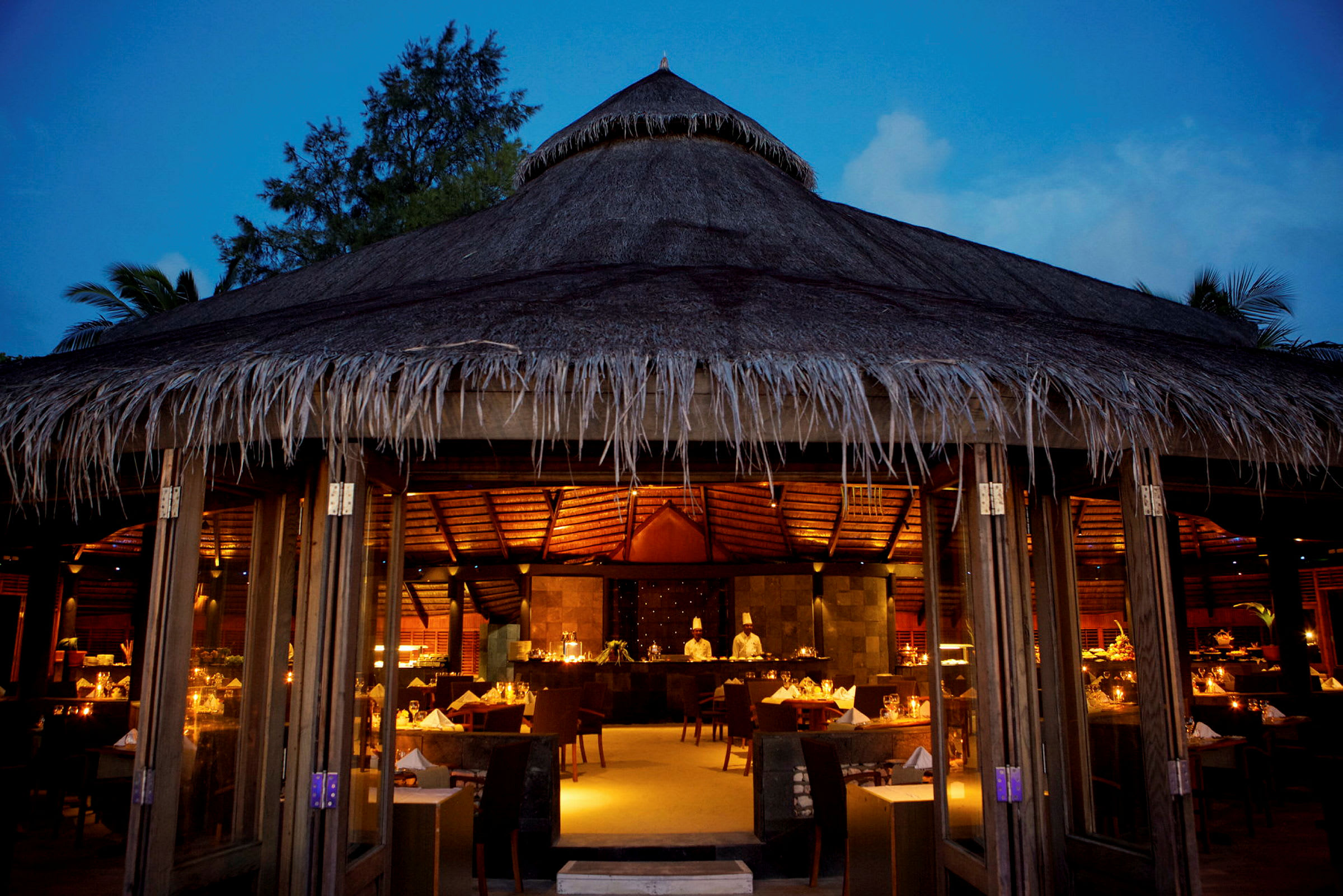 Restaurant med stråtag oplyst af varme lys om aftenen. (AI-genereret tekst)