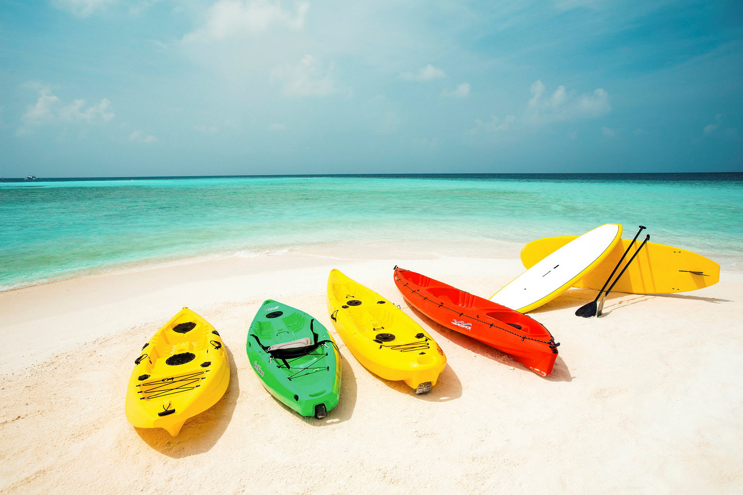 Flere kajakker og et paddleboard på en sandstrand ved havet. (AI-genereret tekst)