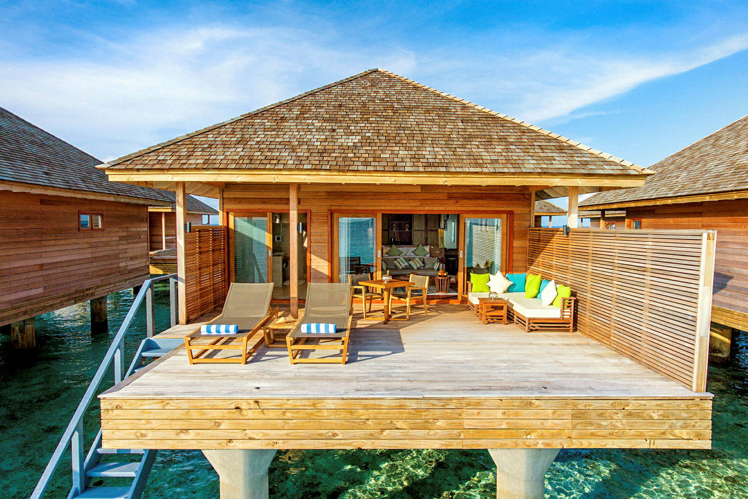 En overwater-bungalow med træterrasse og siddepladser. (AI-genereret tekst)