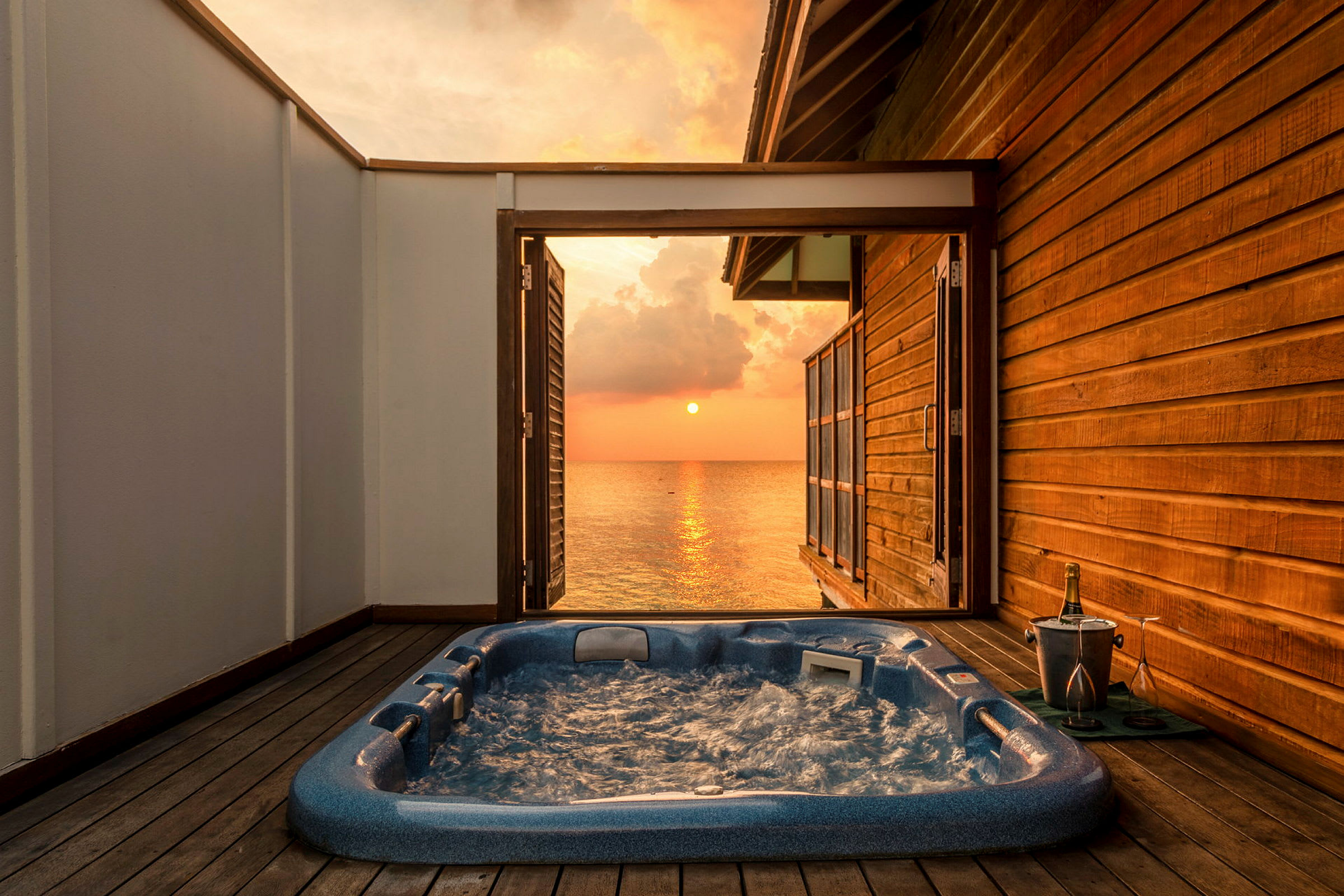 Udendørs jacuzzi på terrasse med udsigt over solnedgangen. (AI-genereret tekst)