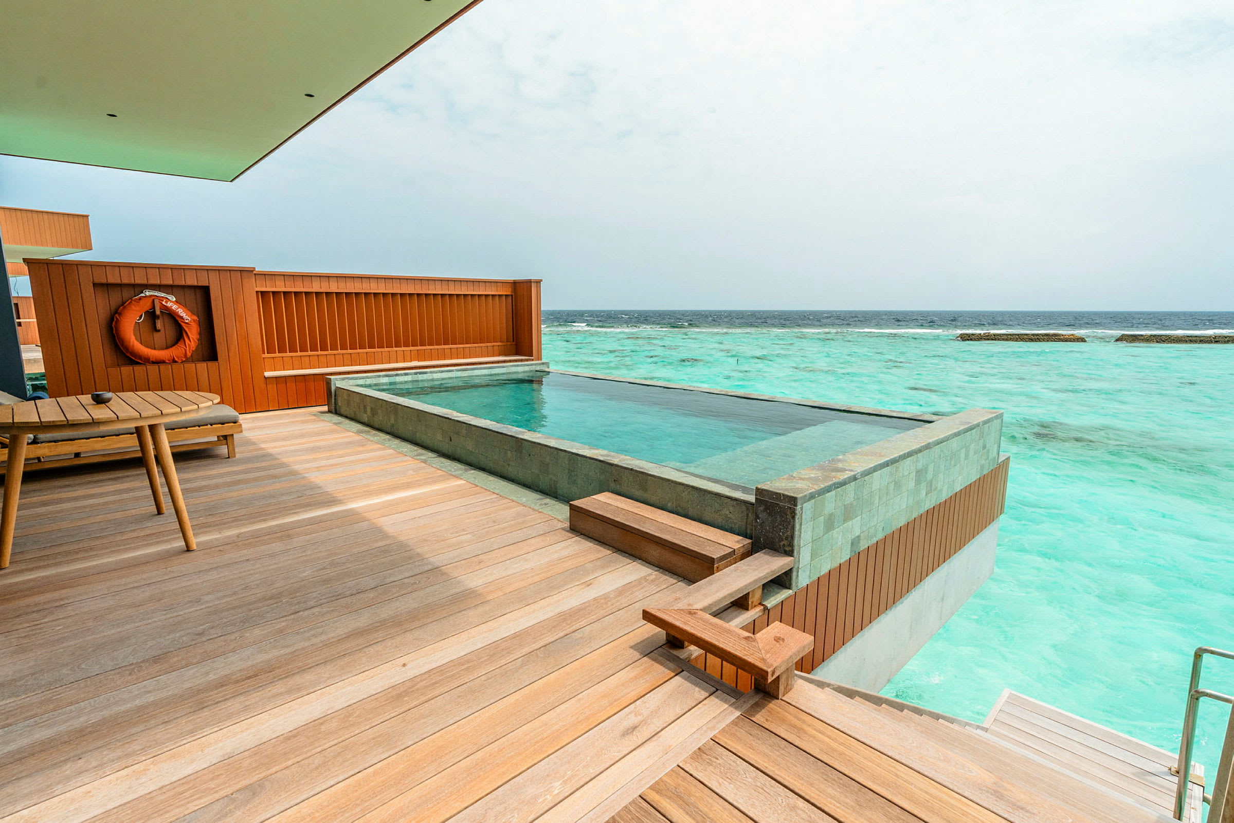 Billede af en terrasse med en privat pool, havet er synligt i baggrunden. (AI-genereret tekst)