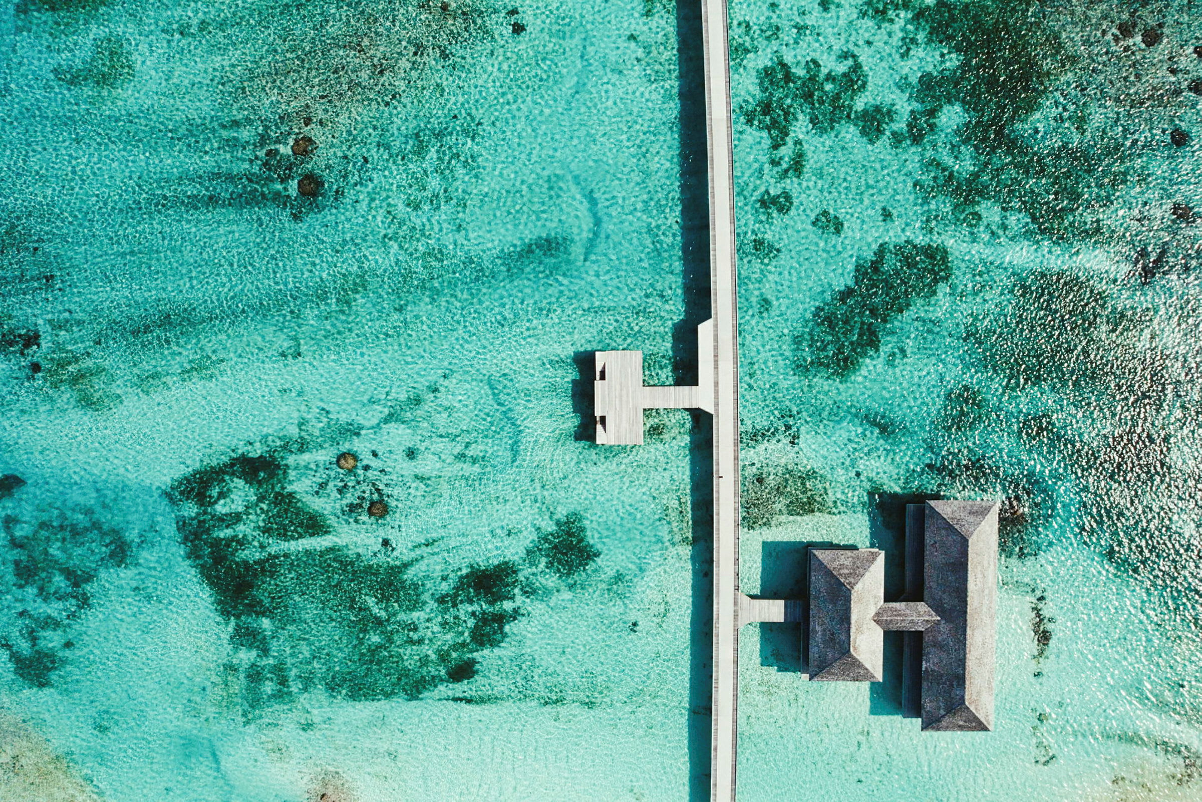 Luftfoto af en bro og overvandshuse omgivet af turkis vand. (AI-genereret tekst)