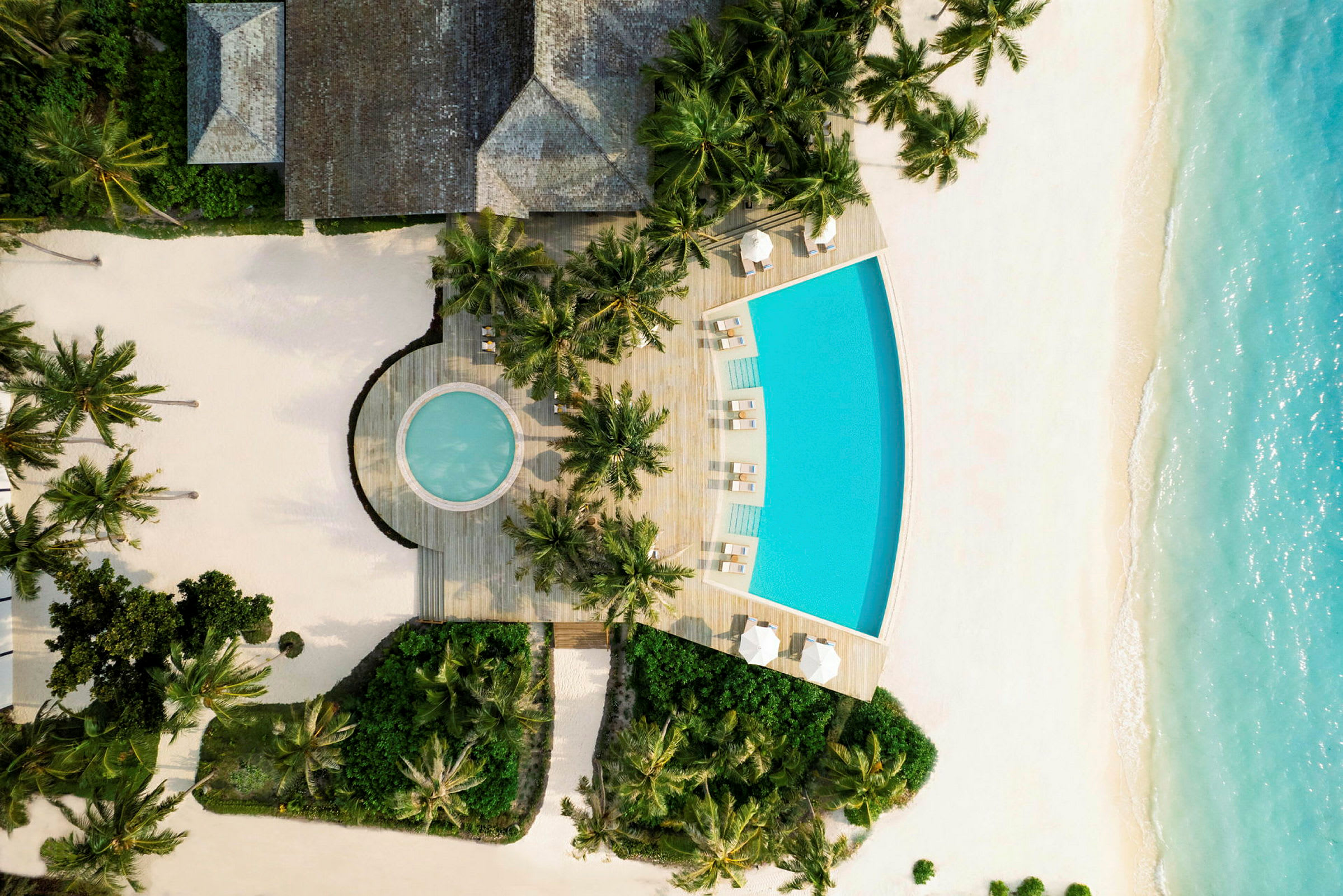 En pool med solsenge omgivet af sandstrand og beplantning. (AI-genereret tekst)