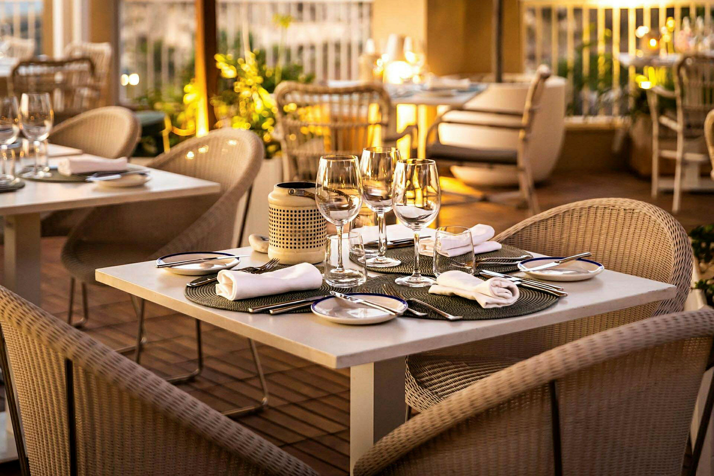Et bord på en elegant restaurant med glas, bestik og tallerkener. Blødt lys og en indbydende atmosfære. (AI-genereret tekst)