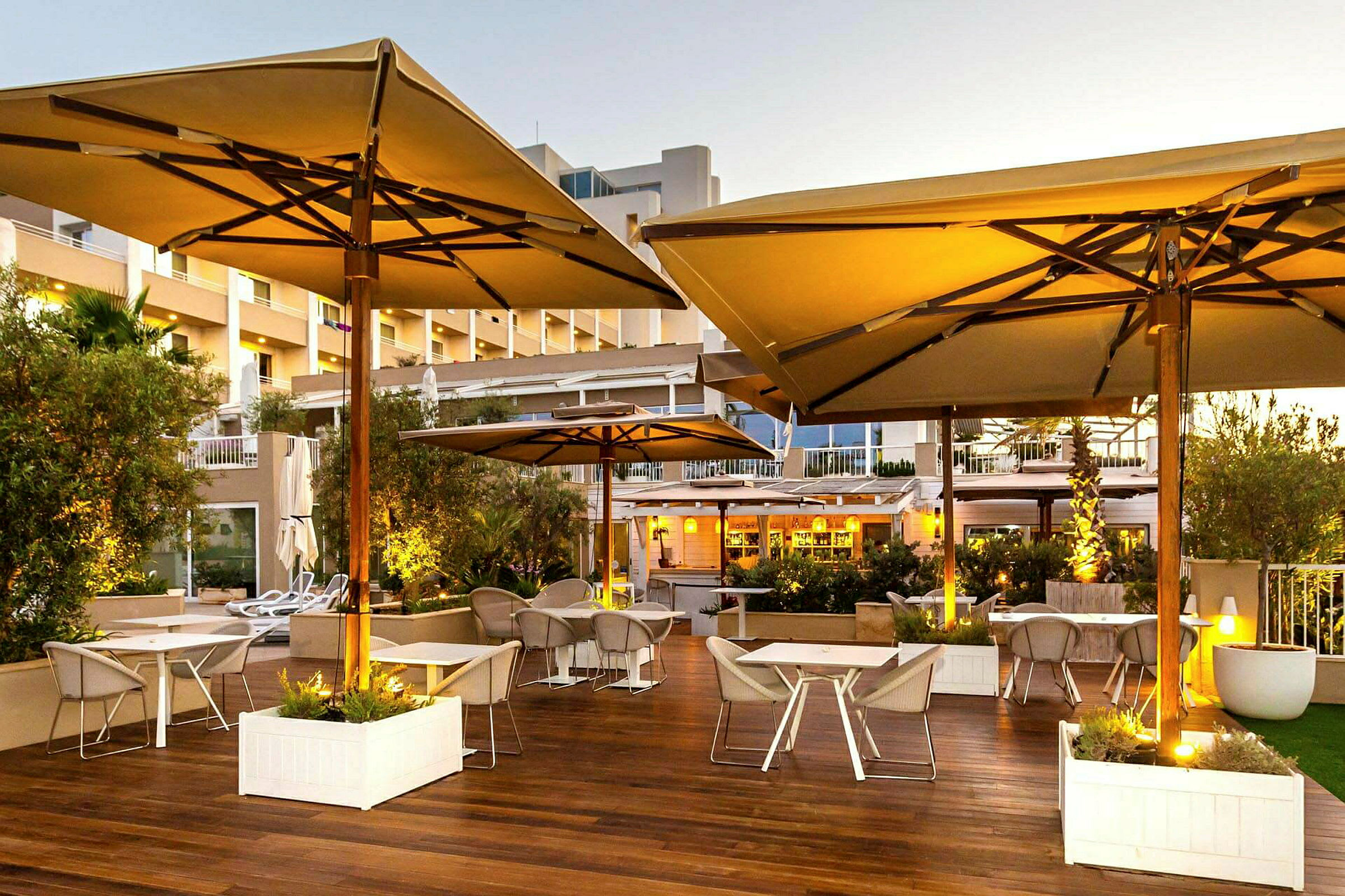 Udendørs terrasse på en restaurant med borde, stole og store parasoller. (AI-genereret tekst)
