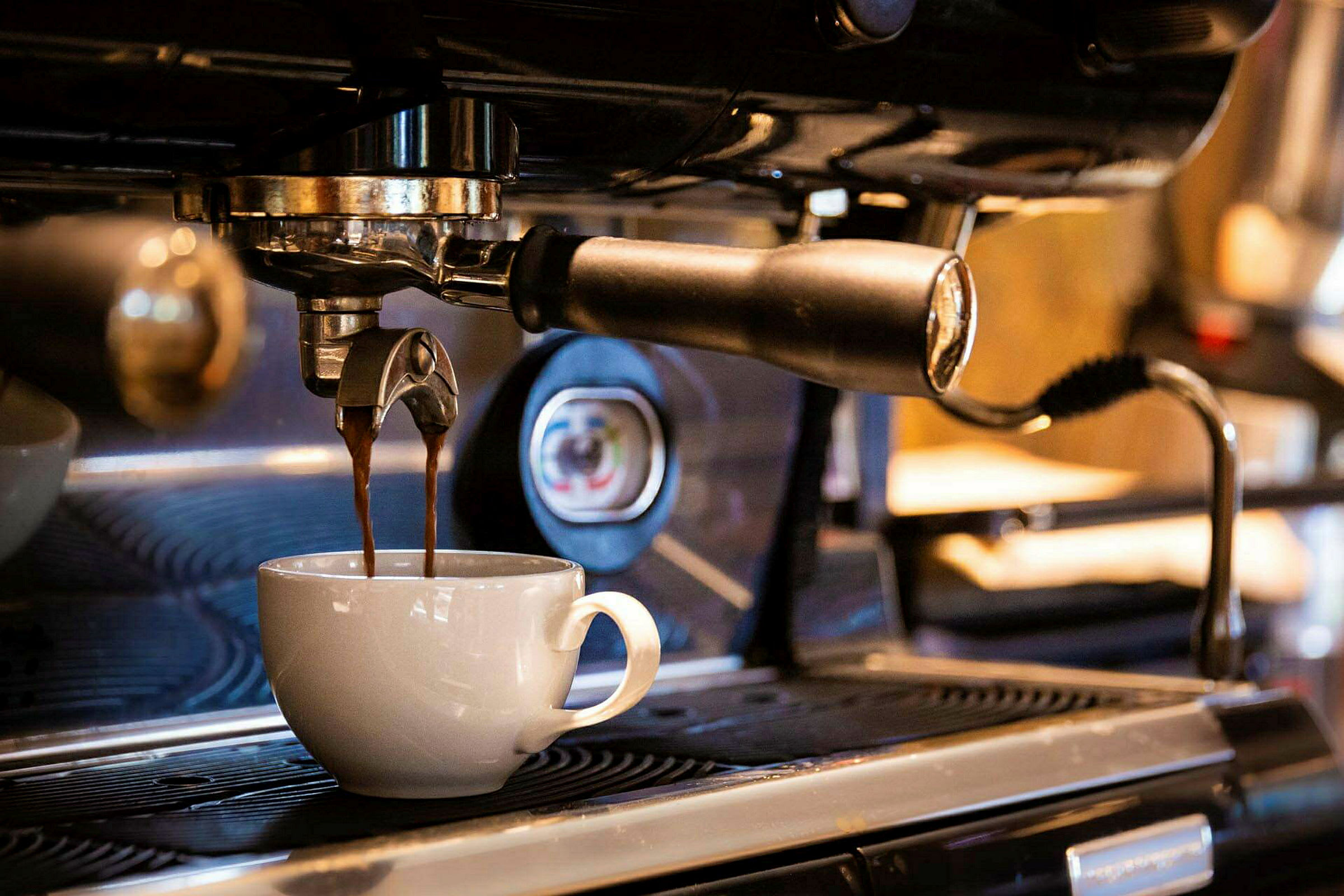 En espressomaskine brygger kaffe, der løber ned i en hvid kop. (AI-genereret tekst)