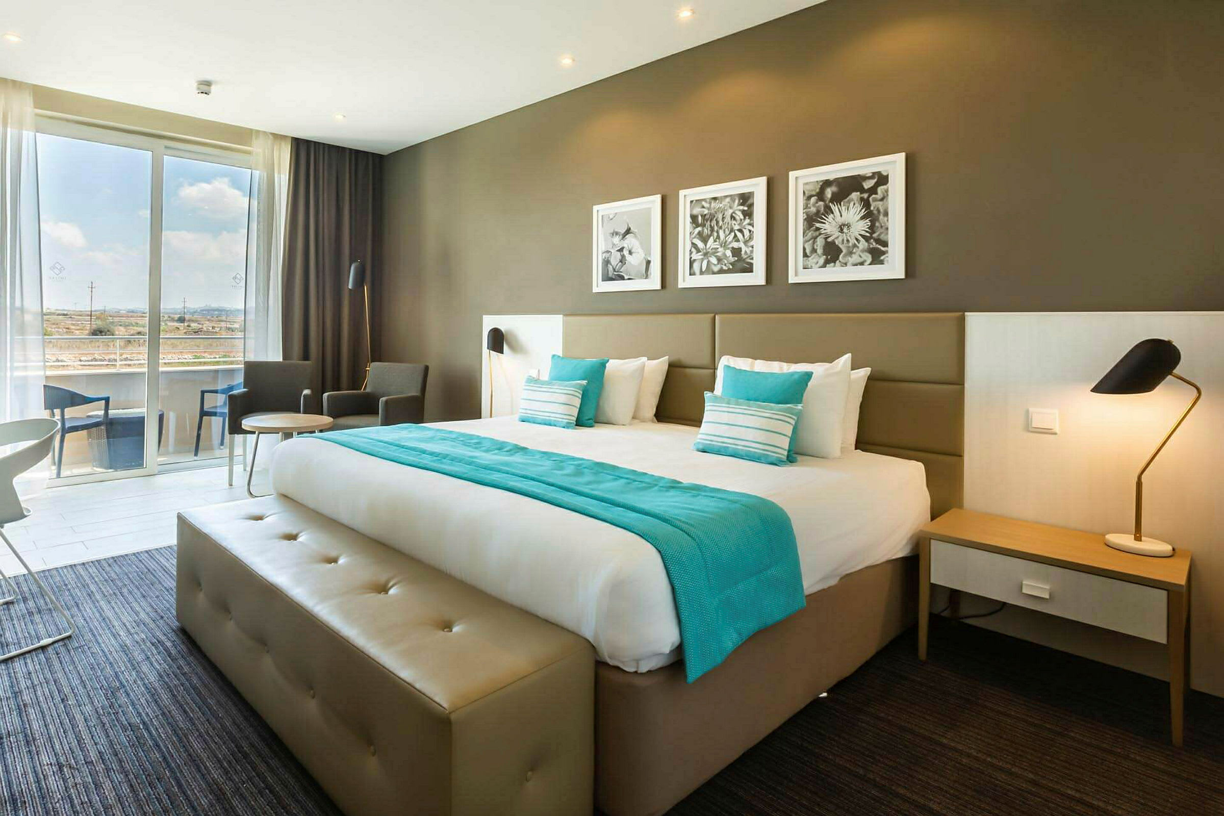 Hotelværelse med en dobbeltseng, siddeområde og store vinduer. (AI-genereret tekst)