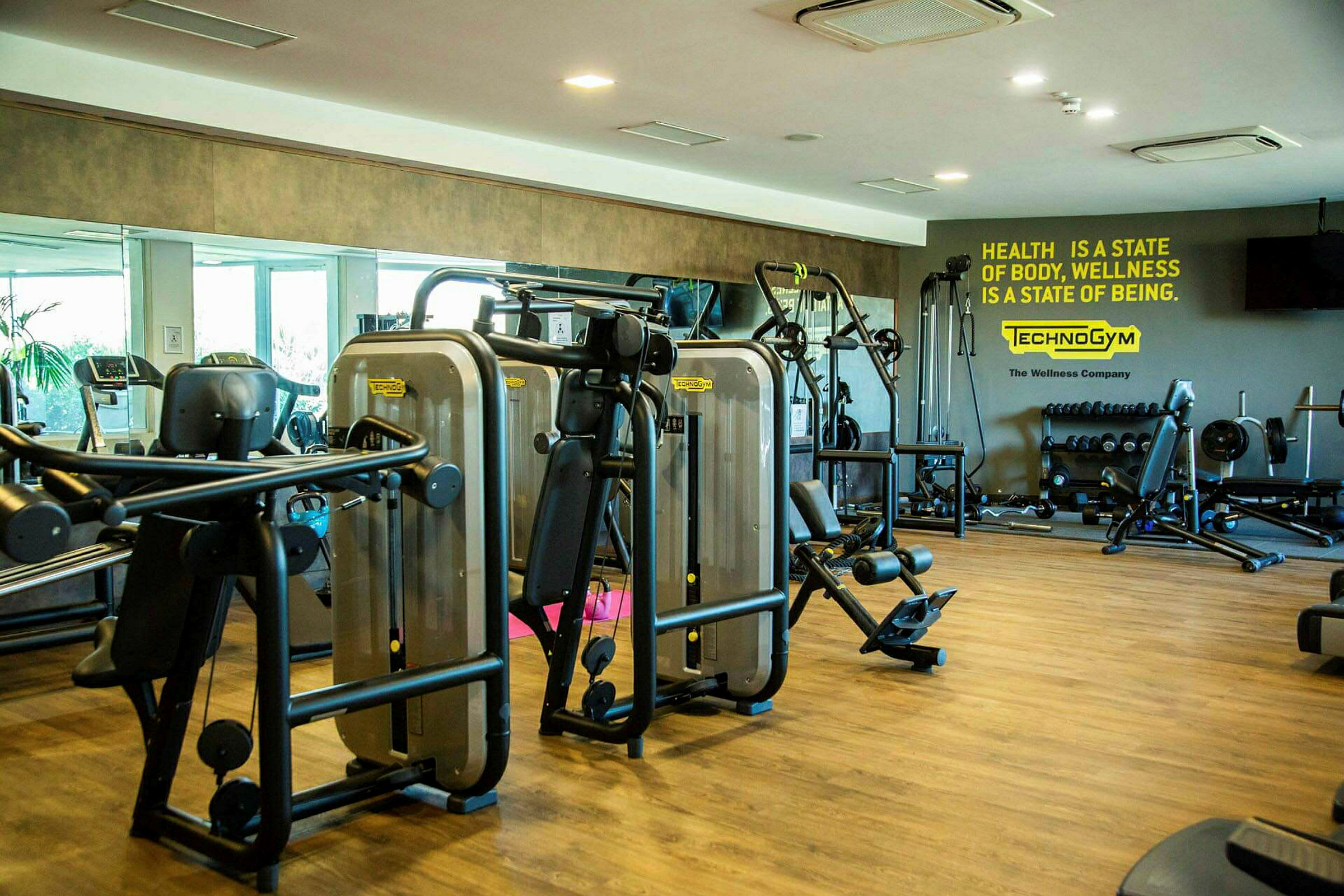 Et fitnesscenter med træningsmaskiner, vægte og spejlvæg. (AI-genereret tekst)