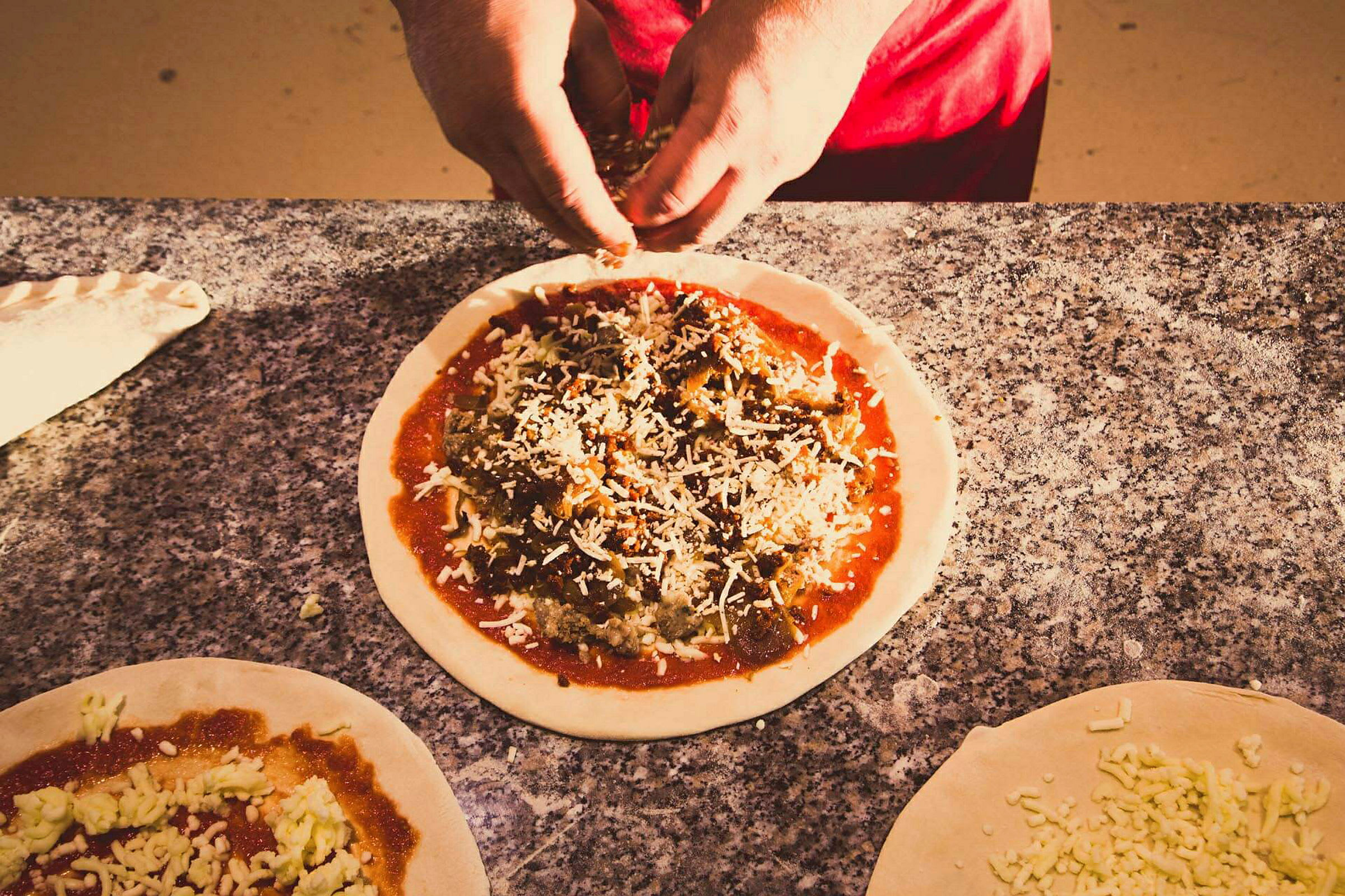 En person forbereder en pizza med fyld på en marmorplade. (AI-genereret tekst)