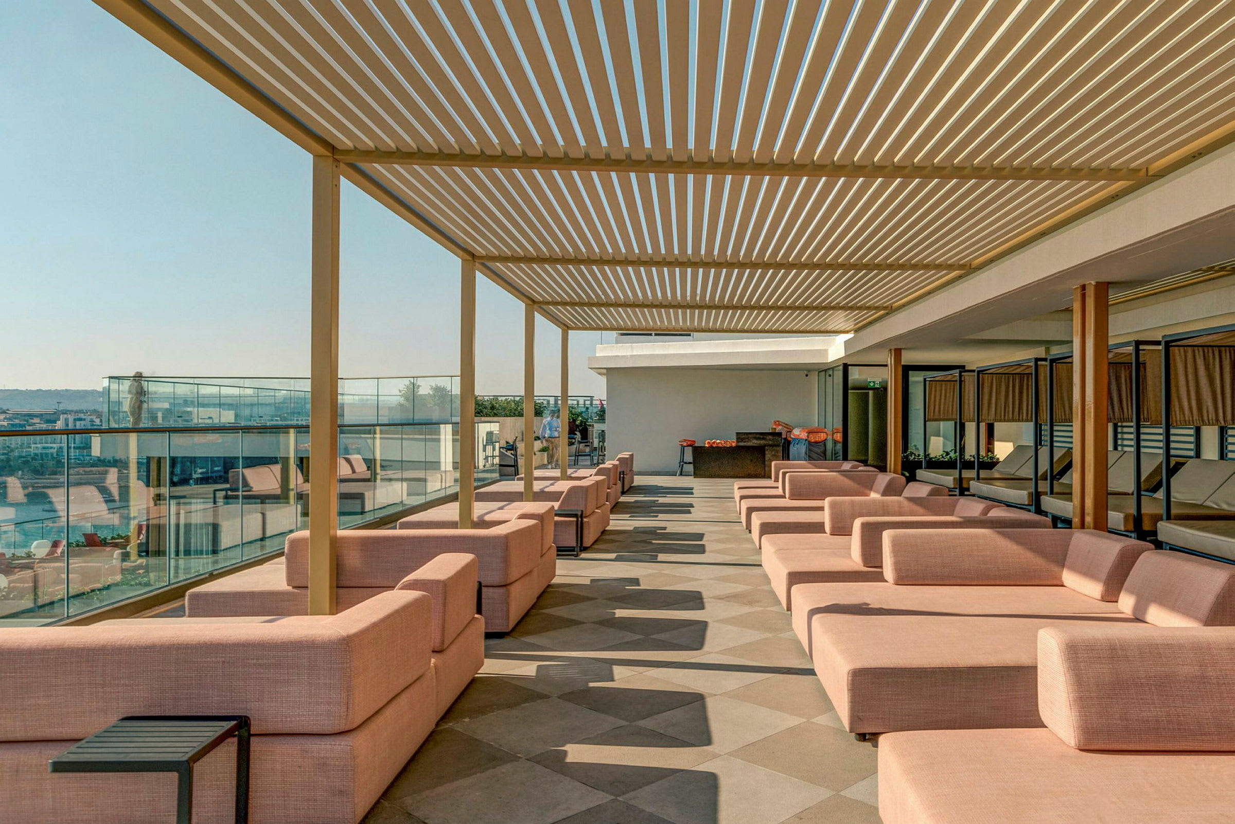 En terrasse med lyserøde siddepladser og en pergola i loftet. (AI-genereret tekst)