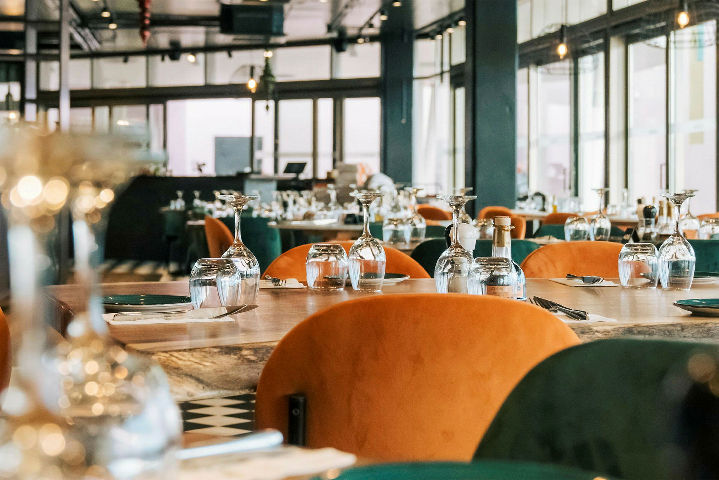 En restaurant med bord dækket med glas og bestik klar til gæster. (AI-genereret tekst)