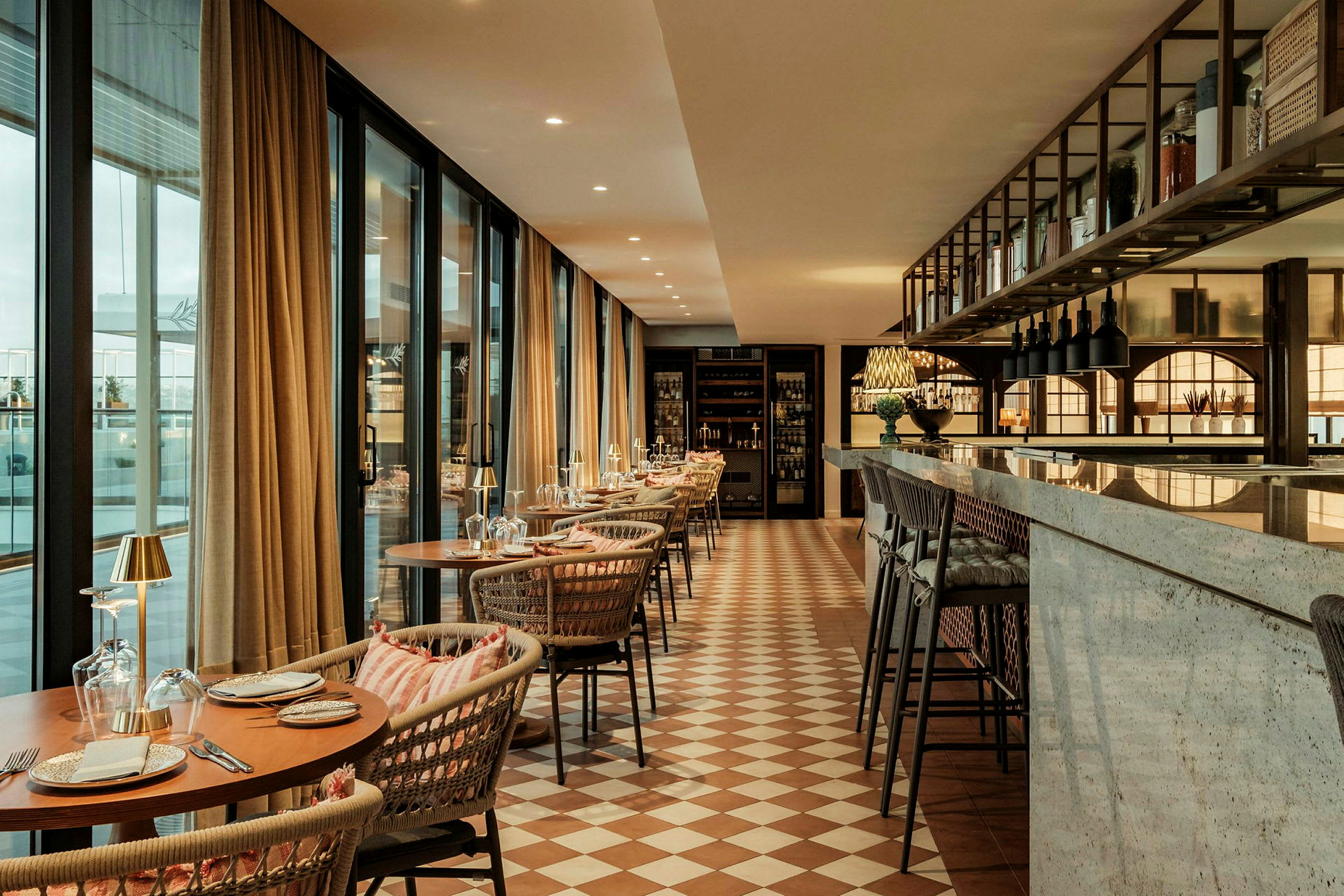 En elegant indrettet restaurant med dækkede borde, behagelige stole, store vinduer og en marmordisk. (AI-genereret tekst)