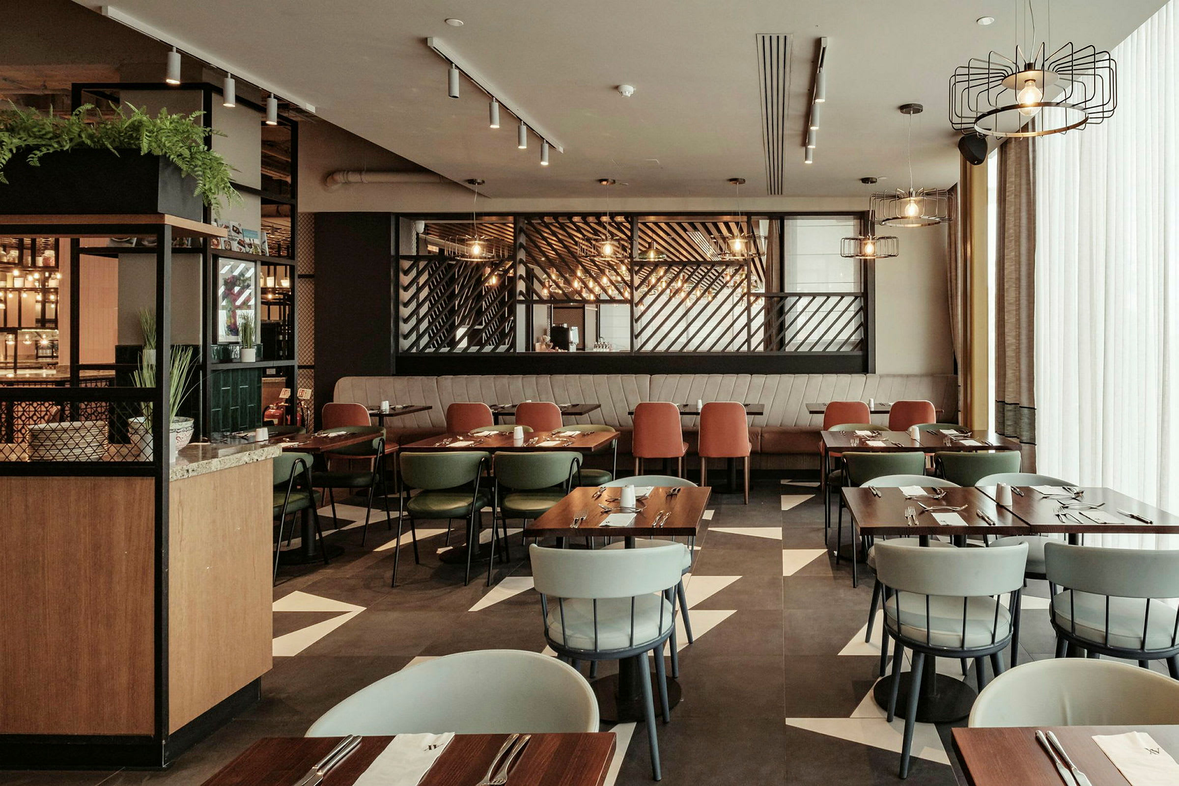 Et moderne indrettet restaurantområde med flere borde og stole, belysning og dekorative elementer. (AI-genereret tekst)