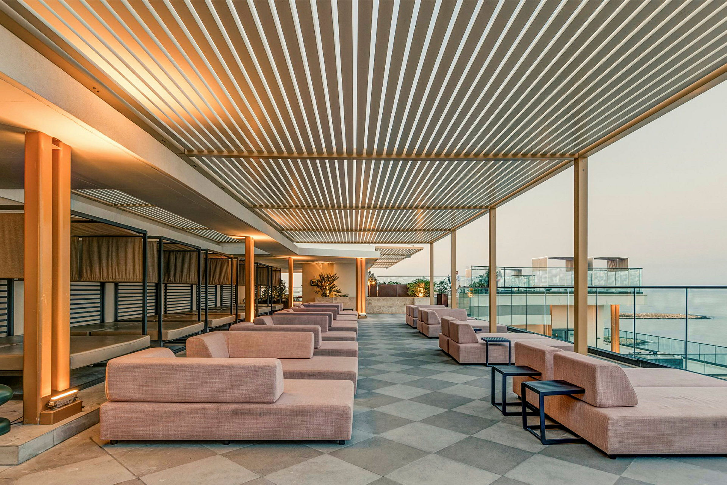 Et moderne tagterrasseområde med brede sofaer og borde, omgivet af åbne områder og glasrækværk. (AI-genereret tekst)