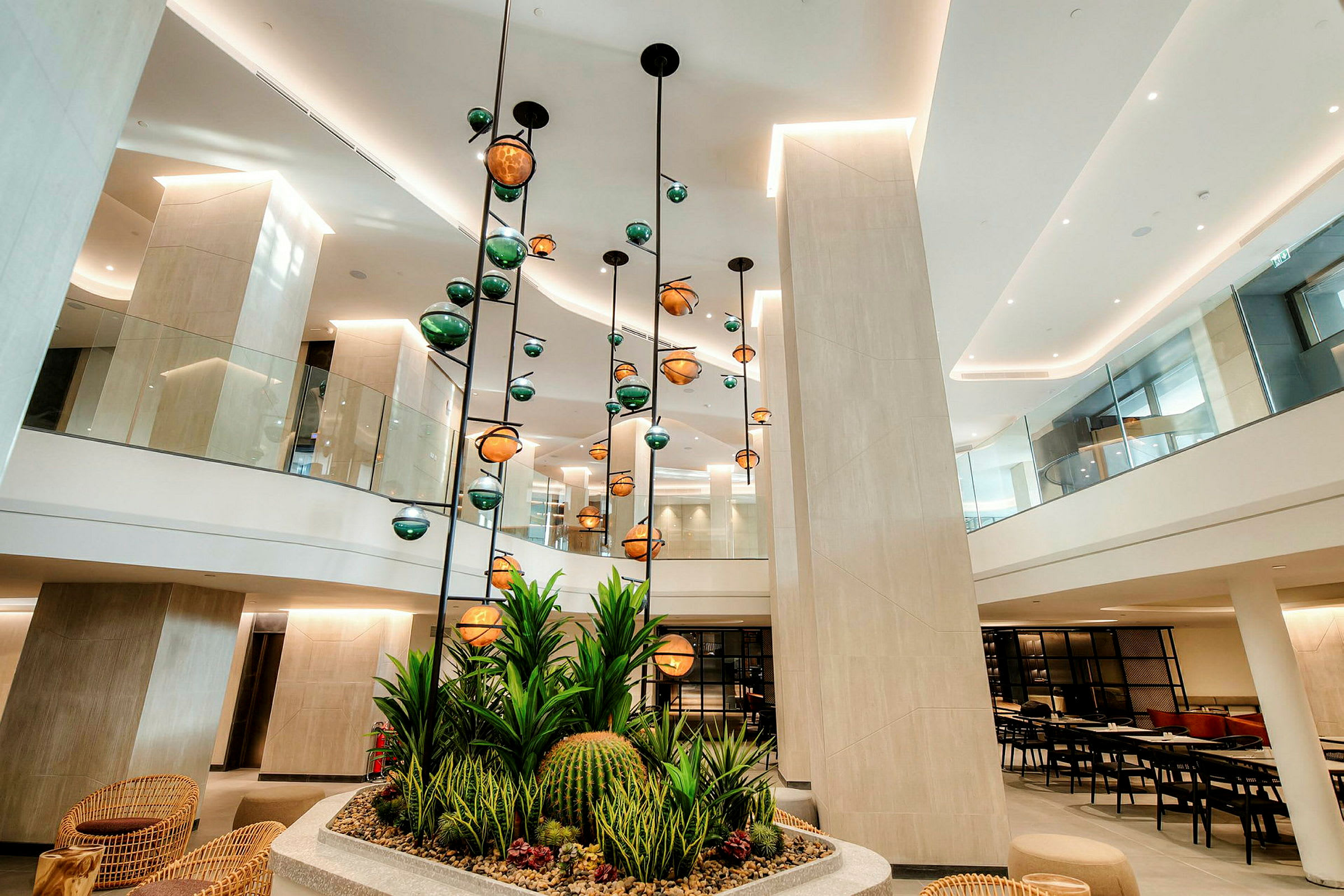 Billede af en moderne hotellobby med hængende lamper og dekorative planter i forgrunden. (AI-genereret tekst)