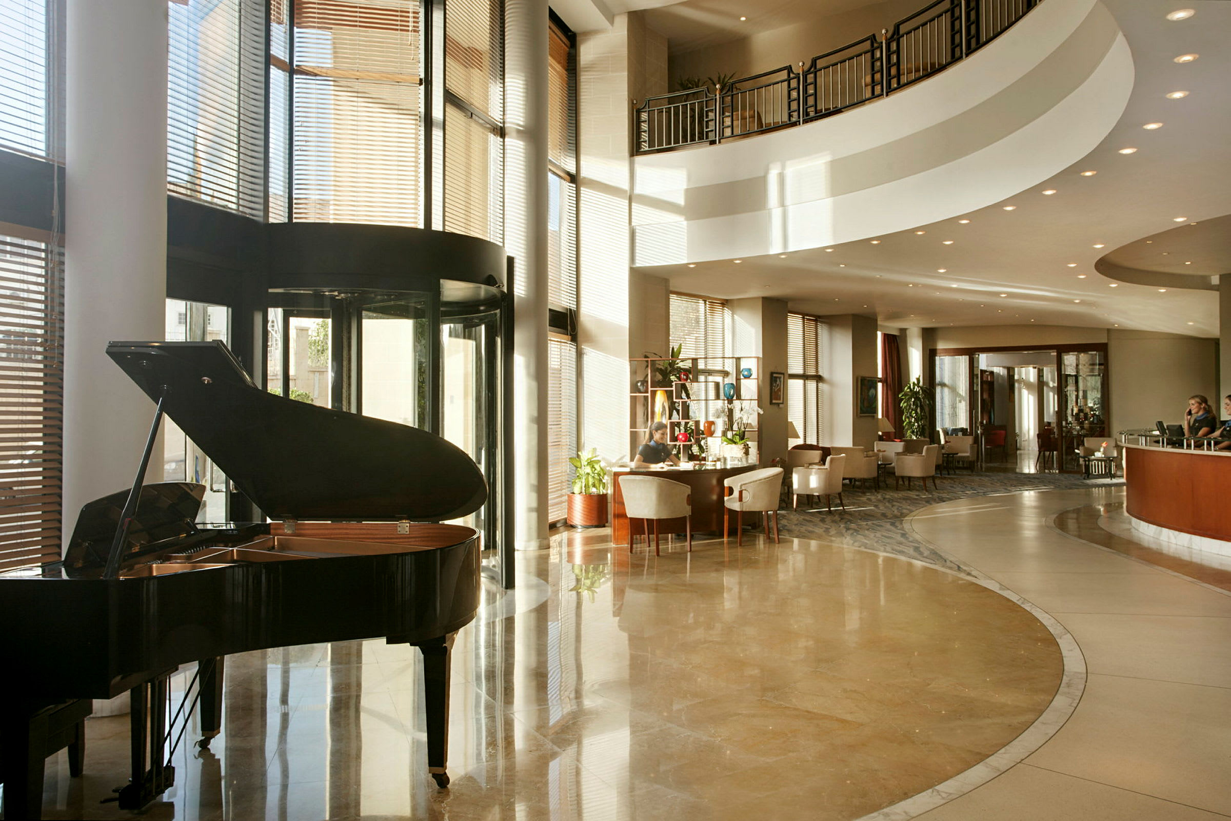Hotellobby med et flygel, siddegrupper og en reception i baggrunden. (AI-genereret tekst)
