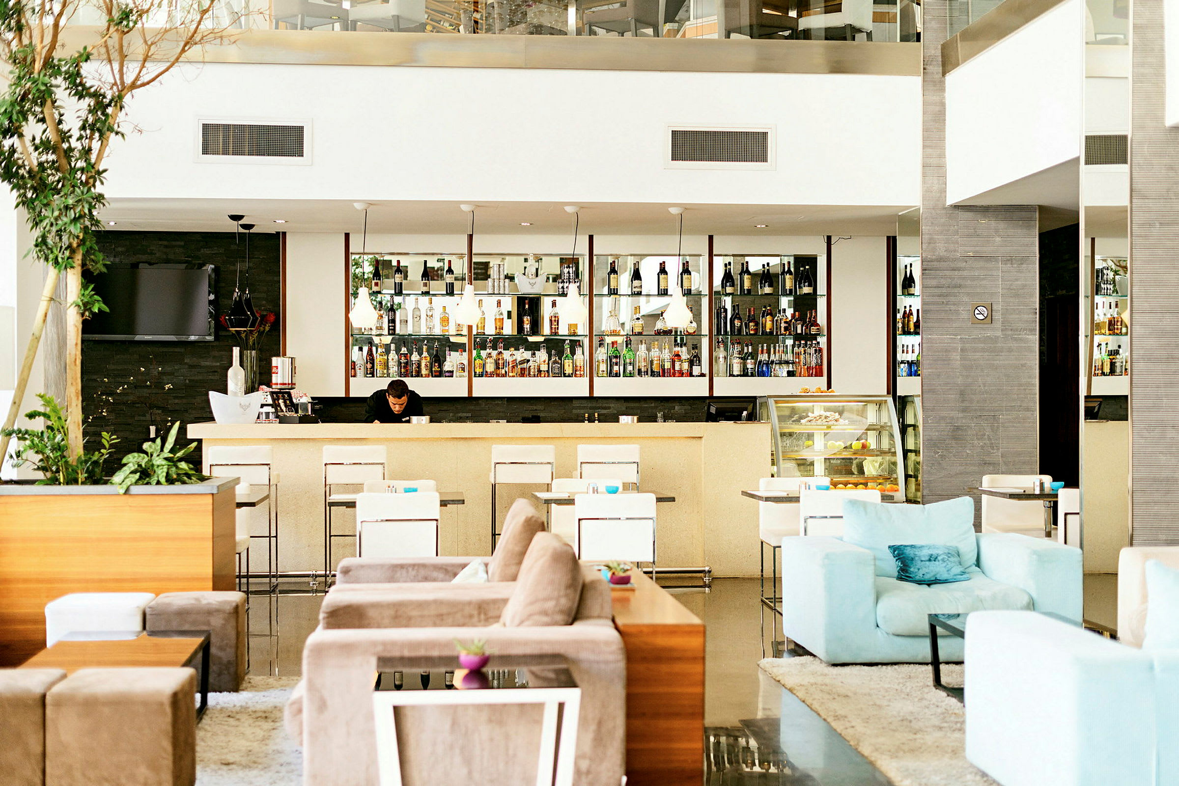En hotellobby med en godt oplyst bar, moderne siddepladser og en afslappet atmosfære. (AI-genereret tekst)
