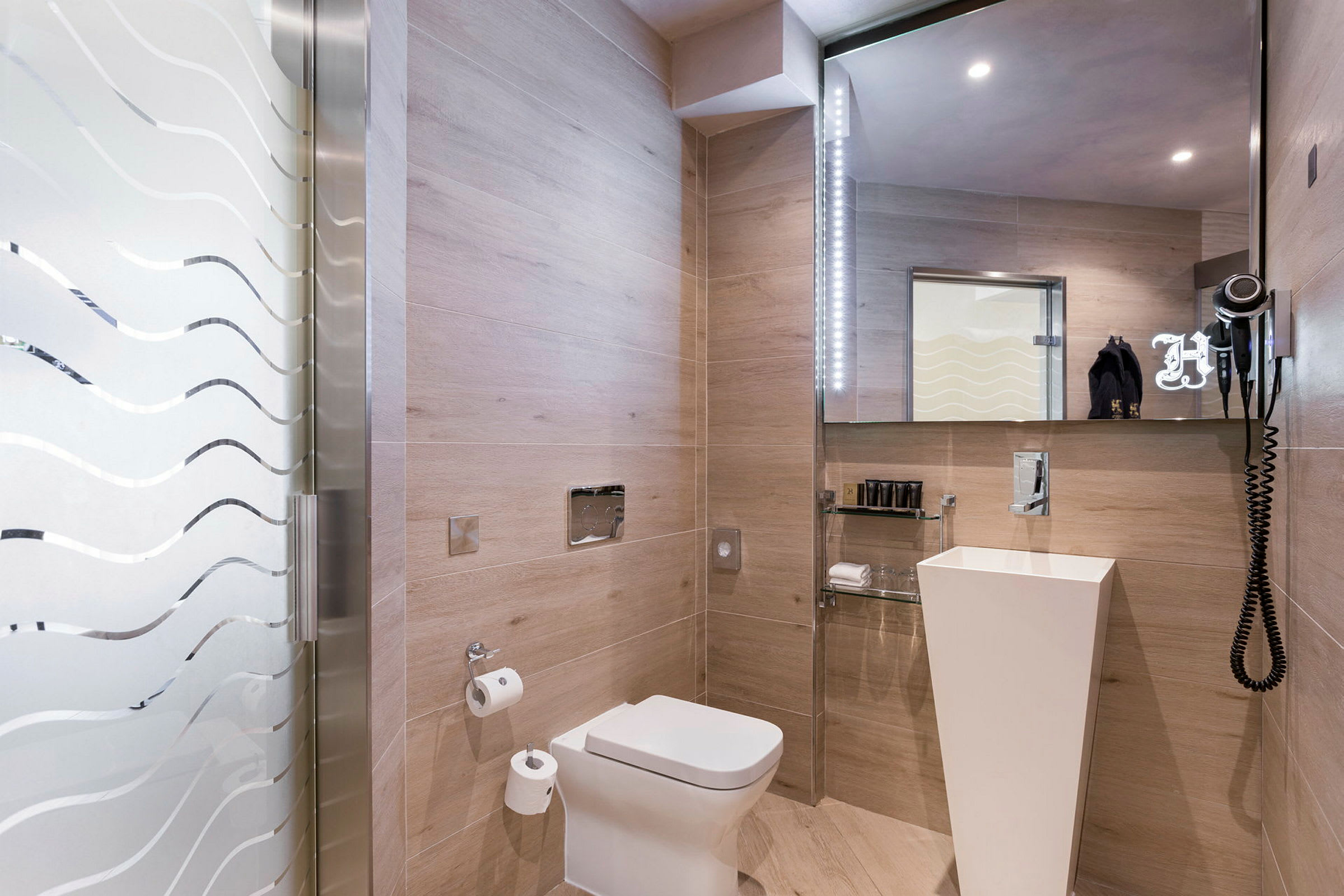 Moderne badeværelse med glasdør, toilet, håndvask og spejl. (AI-genereret tekst)