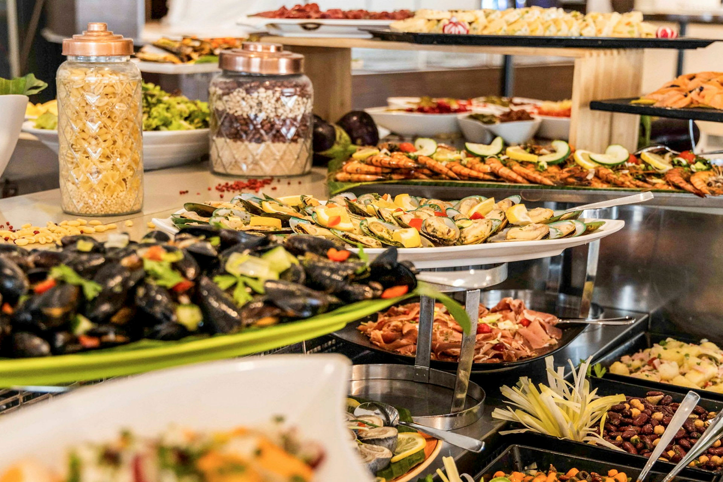 En buffet med forskellige retter såsom muslinger, rejer og pastasalat. (AI-genereret tekst)