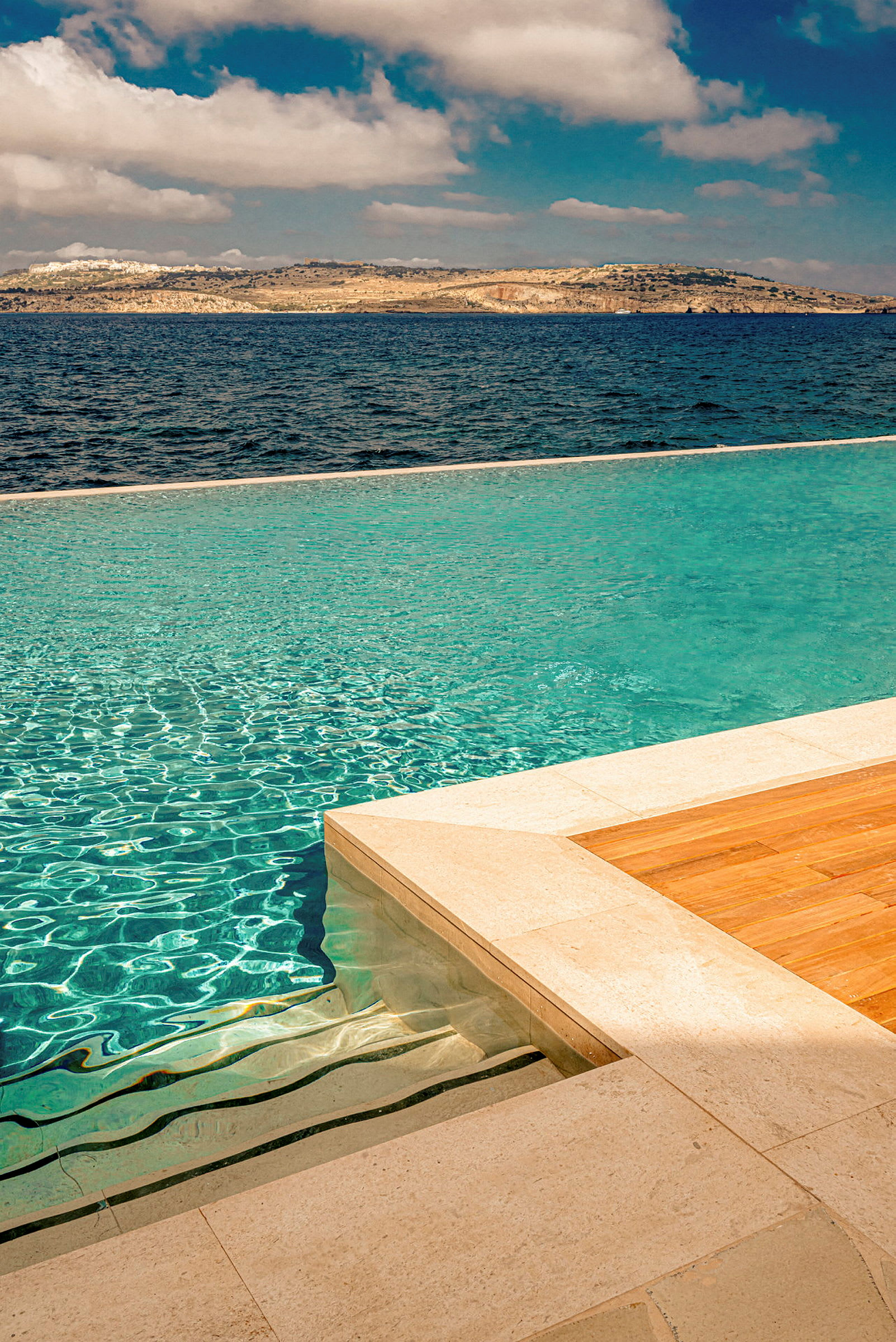 Infinitypool med udsigt over havet og en bjergrig kyst. (AI-genereret tekst)