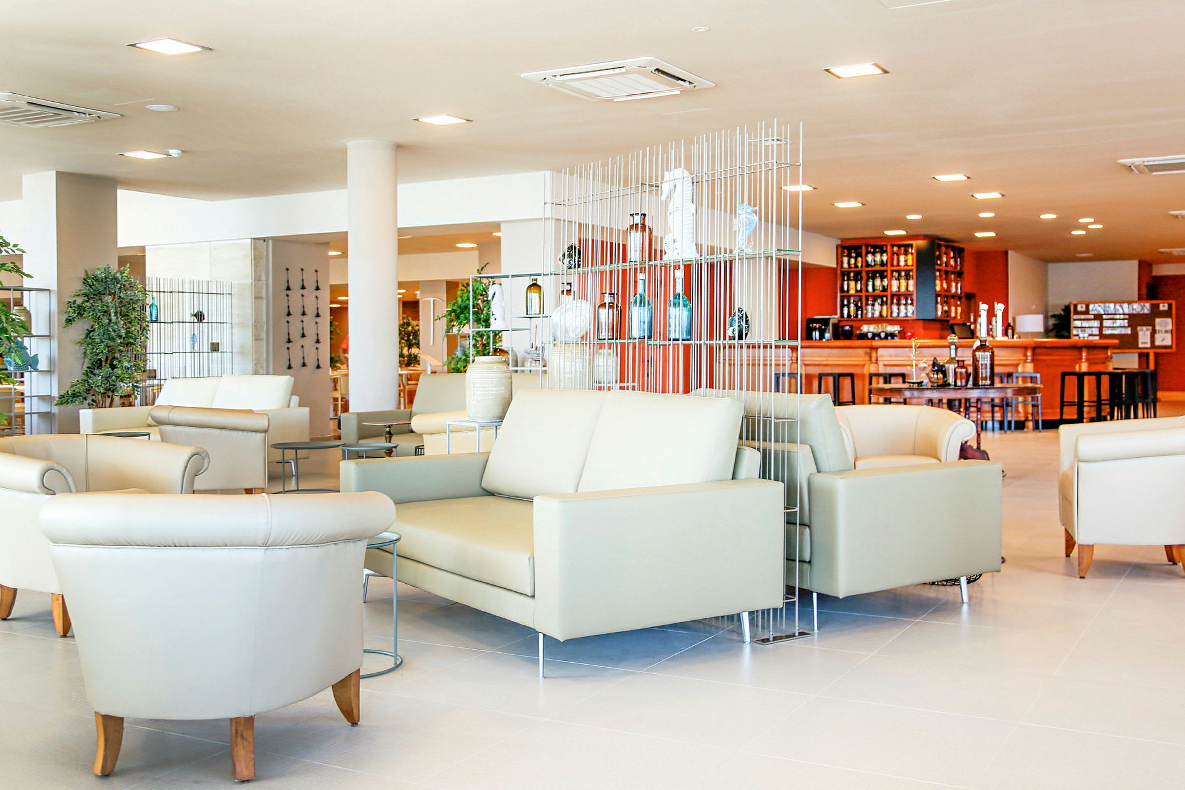 Lys og moderne lounge med sofaer og lænestole samt en bar i baggrunden. (AI-genereret tekst)