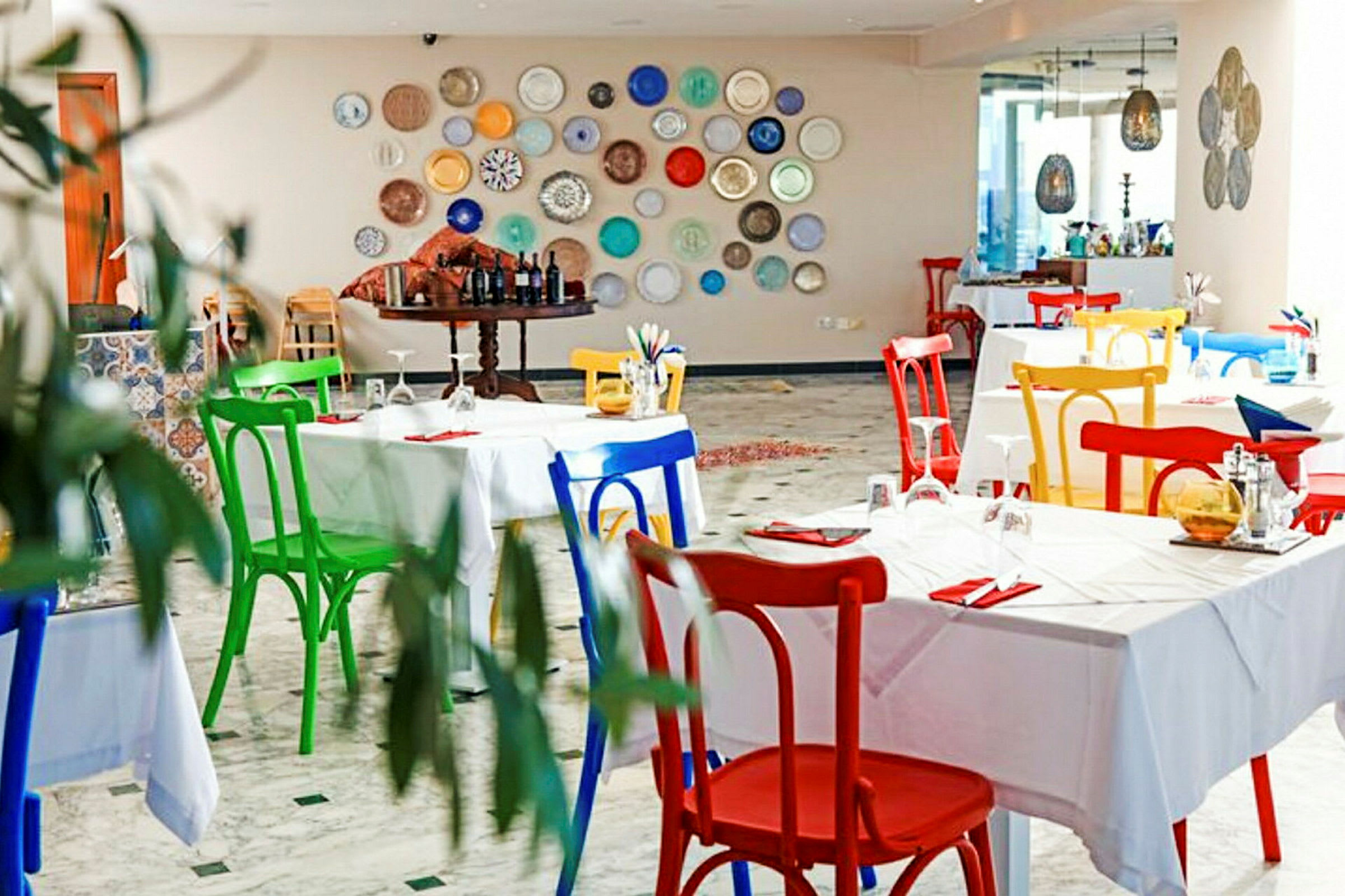 En restaurant med farverige stole og pyntetallerkener på væggen. (AI-genereret tekst)