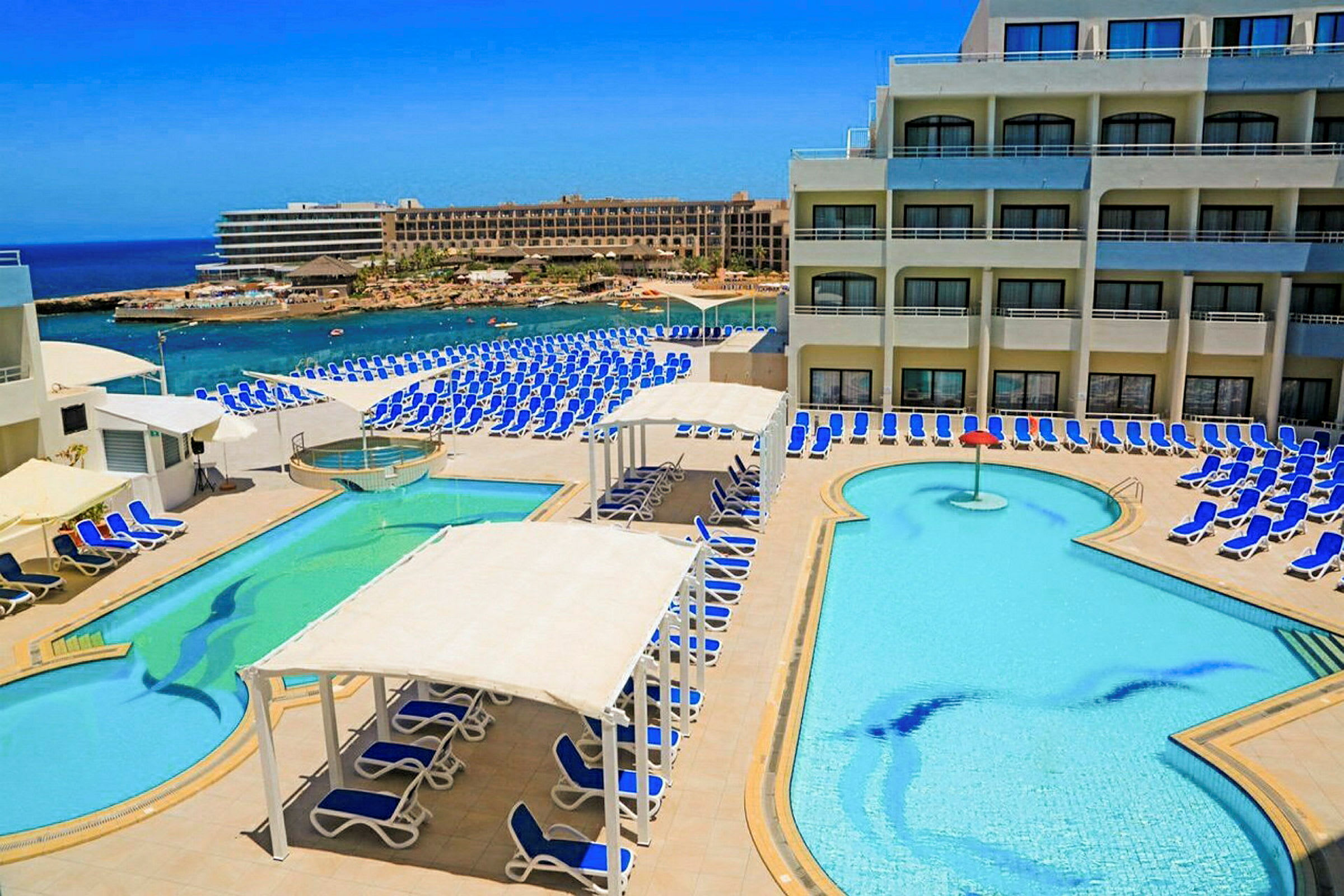 En hotelpool med liggestole og havudsigt. (AI-genereret tekst)