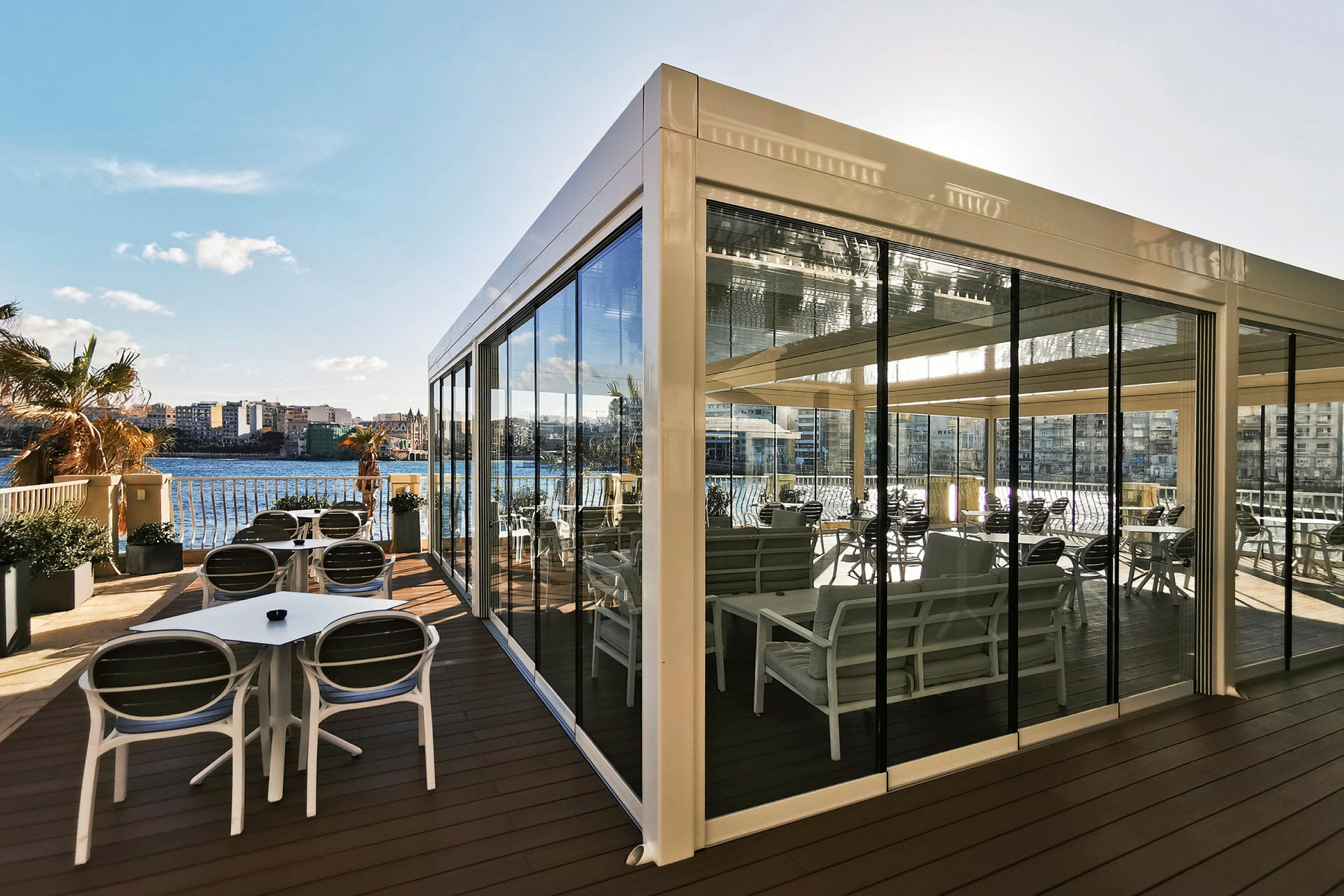 En overdækket terrasse med siddepladser og udsigt over vandet. (AI-genereret tekst)