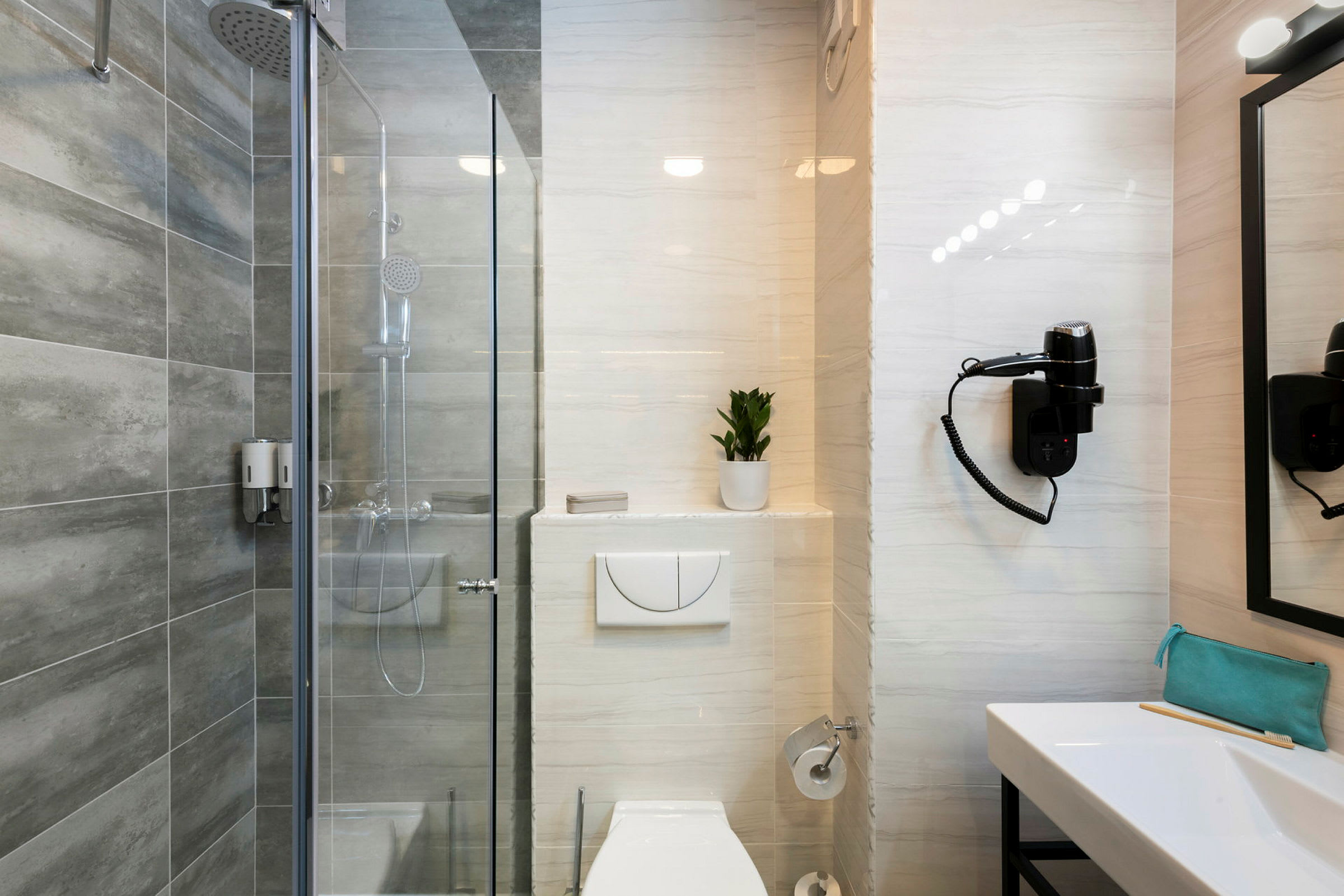 Hotelbadeværelse med bruser, toilet, håndvask og spejl. (AI-genereret tekst)