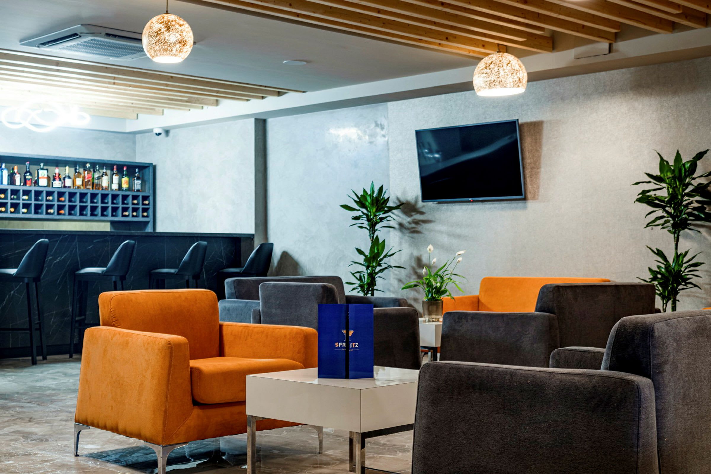 Et moderne loungeområde med farverige stole, borde og en bar i baggrunden. (AI-genereret tekst)
