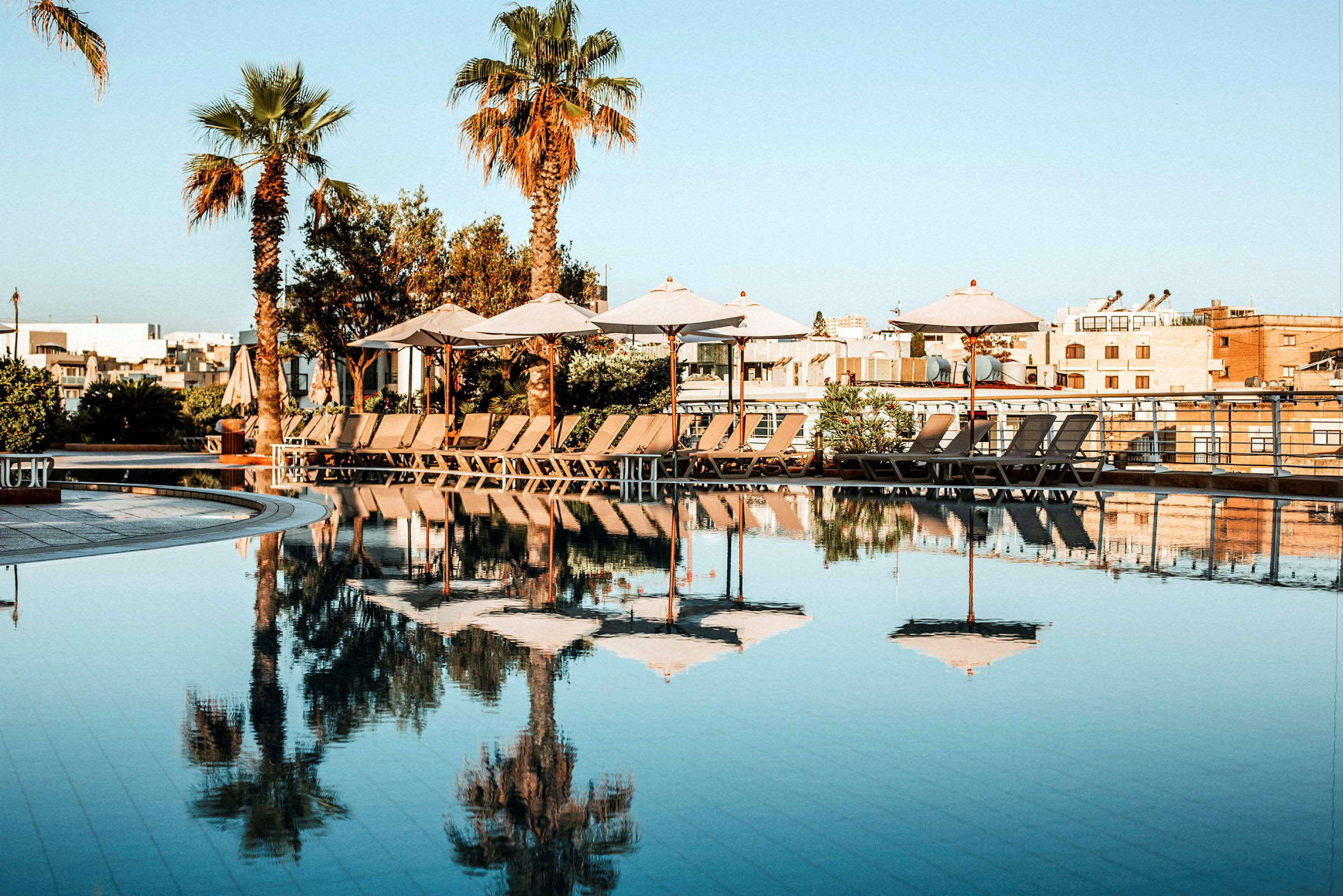 En pool med parasoller og liggestole på en solrig dag. (AI-genereret tekst)