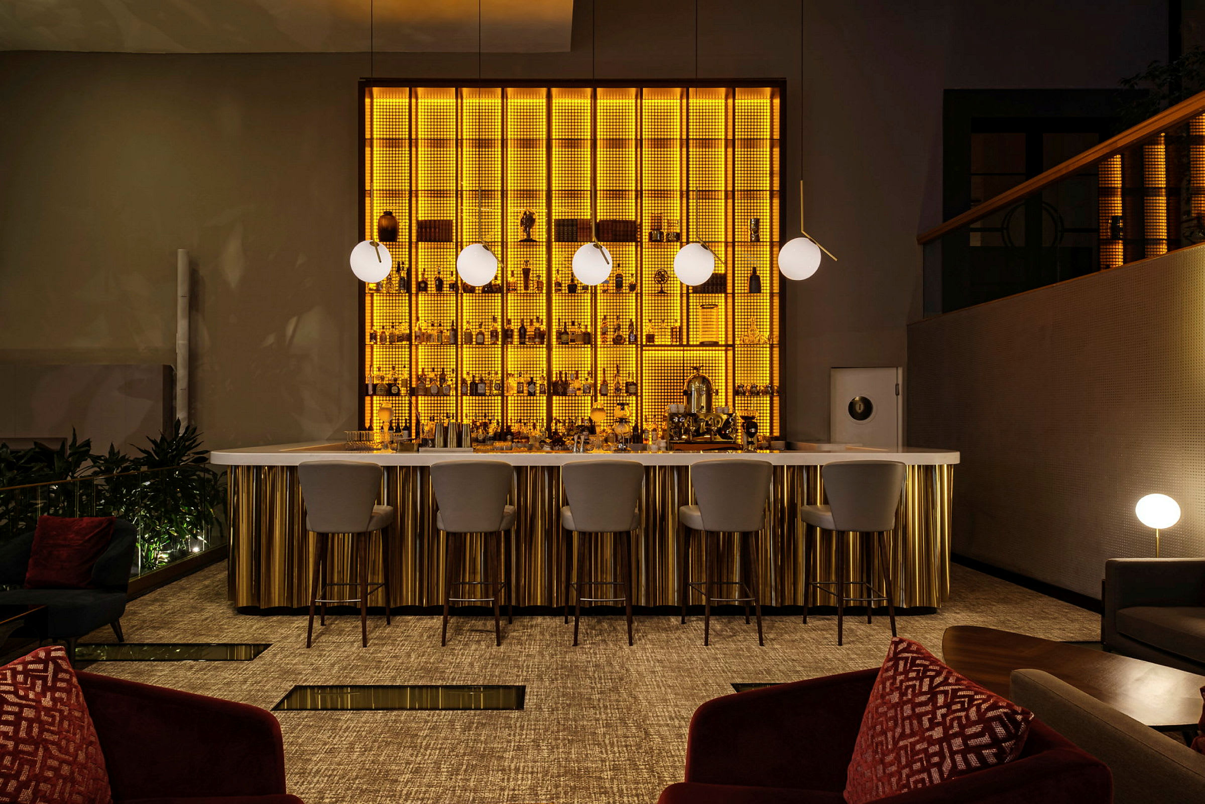 En elegant bardisk med oplyste hylder bagved, moderne lamper og komfortable stole. (AI-genereret tekst)