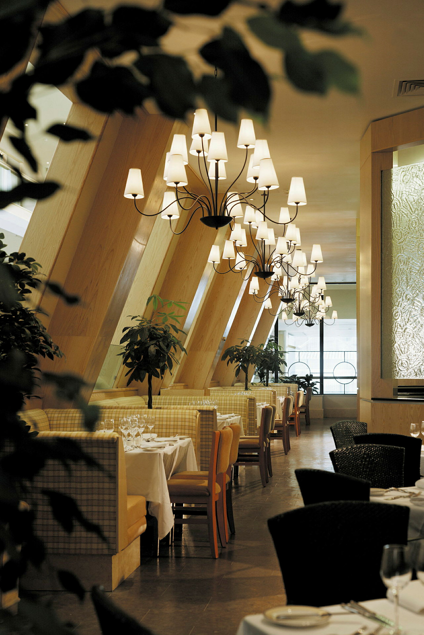 Billede af en elegant restaurant med opdækkede borde, lysekroner og grønne planter. (AI-genereret tekst)