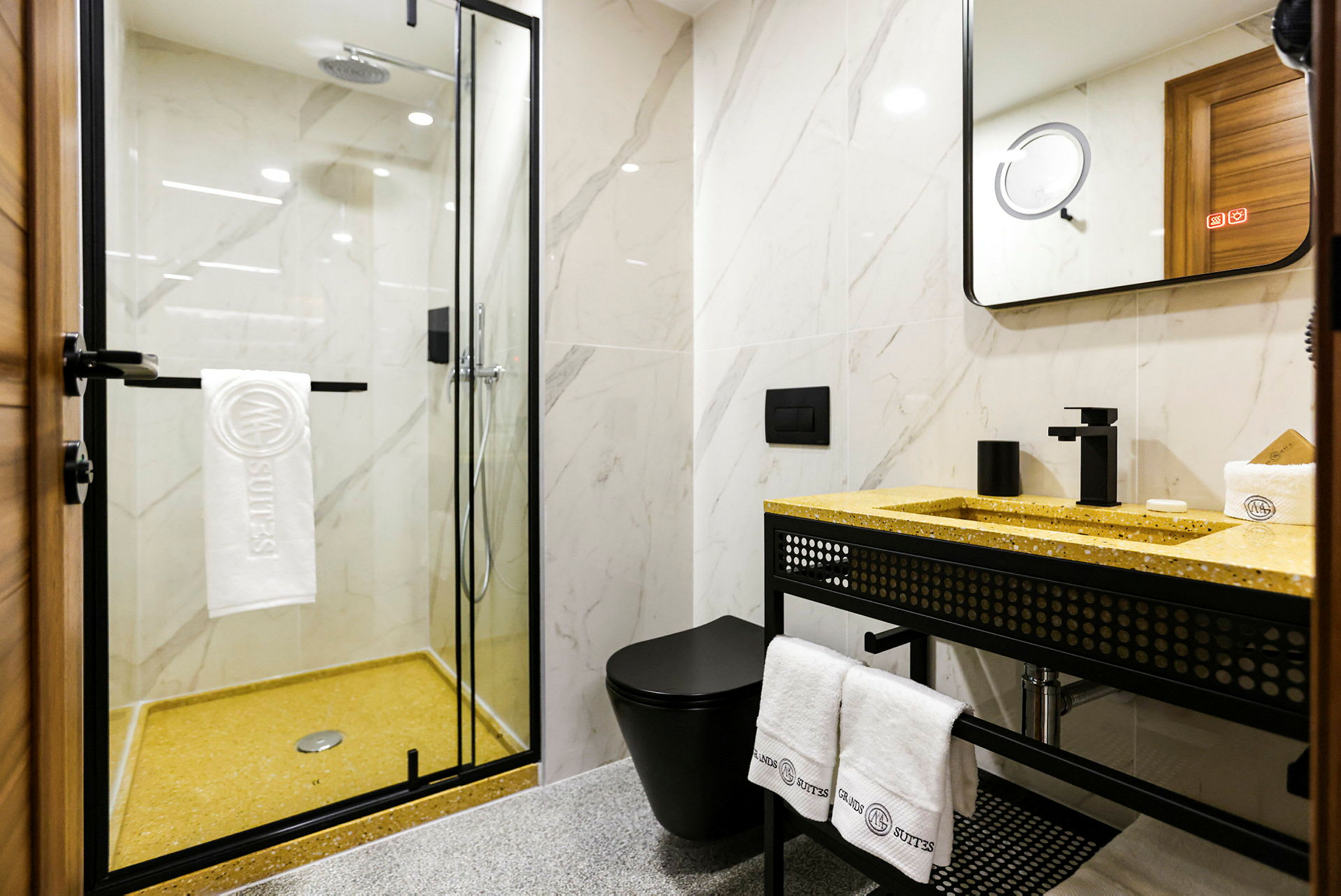 Moderne badeværelse med bruseniche med glasvæg, sort toilet og gul vaskebordplade. (AI-genereret tekst)