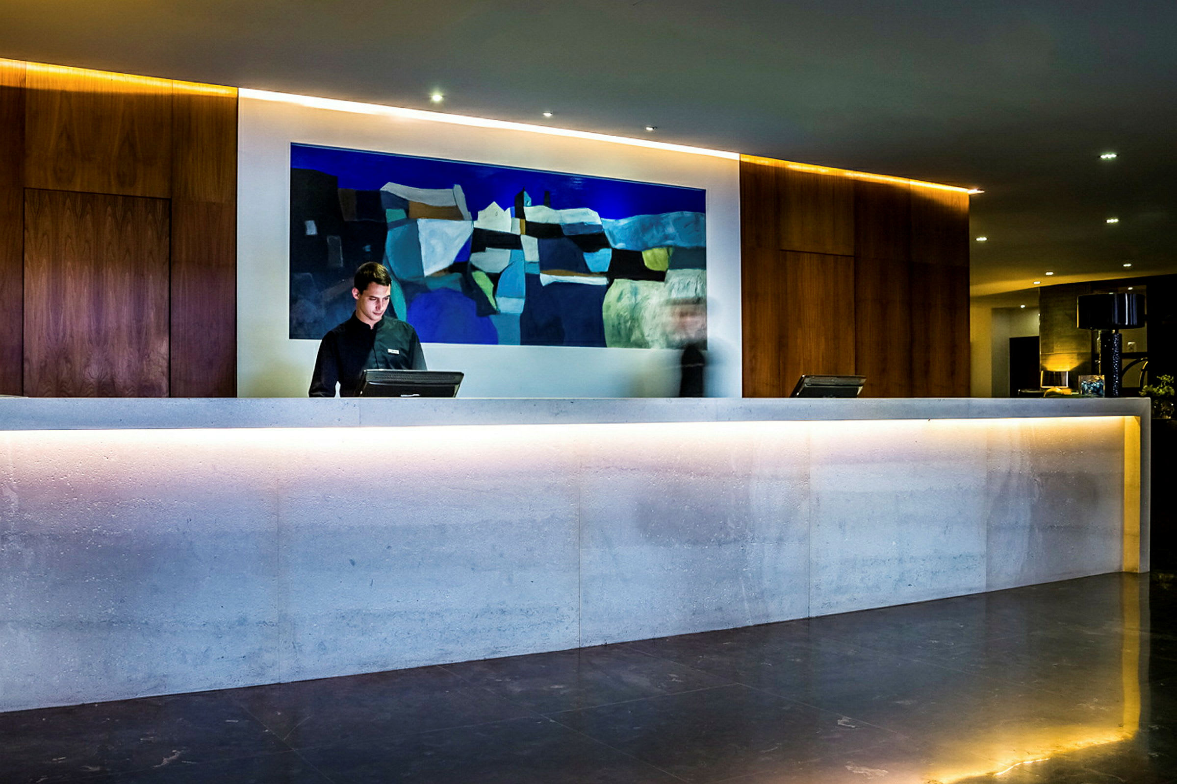 Reception med en oplyst skranke og abstrakt kunst på væggen. (AI-genereret tekst)
