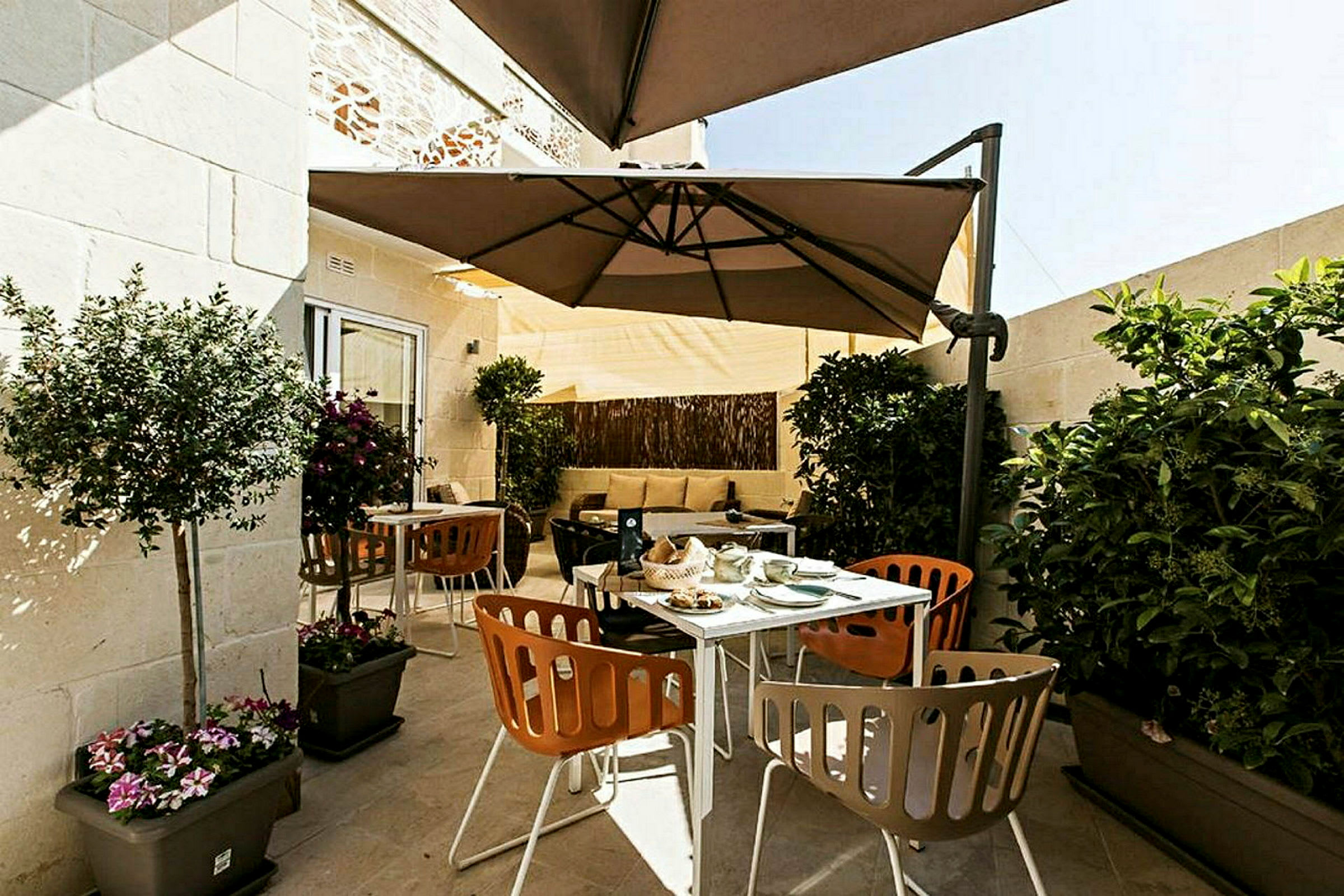 En terrasse med udendørsmøbler, parasoller og planter. (AI-genereret tekst)