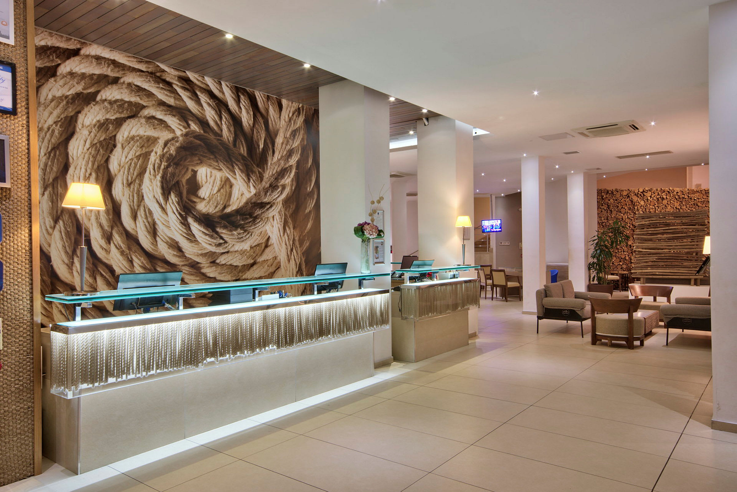 Hotelreception med moderne indretning, store rebdekorationer på væggen og siddegrupper i baggrunden. (AI-genereret tekst)