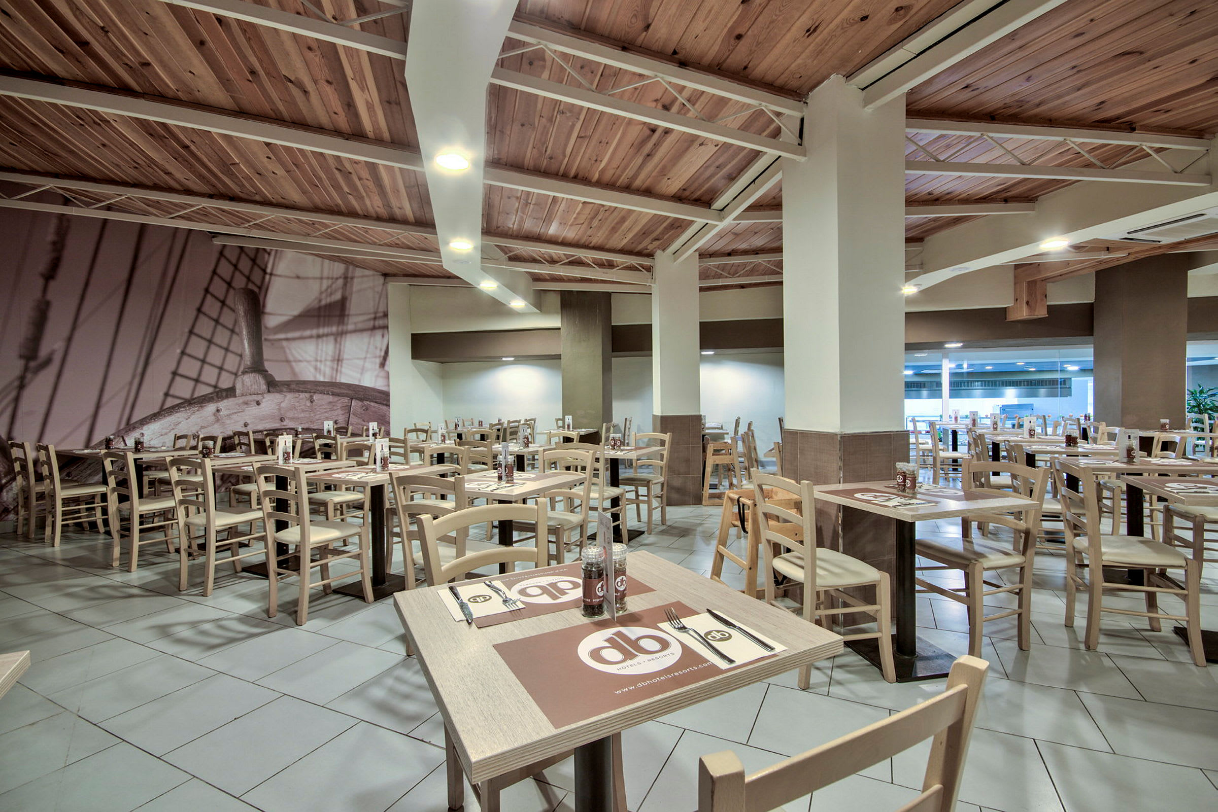 Restaurant med træborde og stole samt vægdekoration af et skib. (AI-genereret tekst)