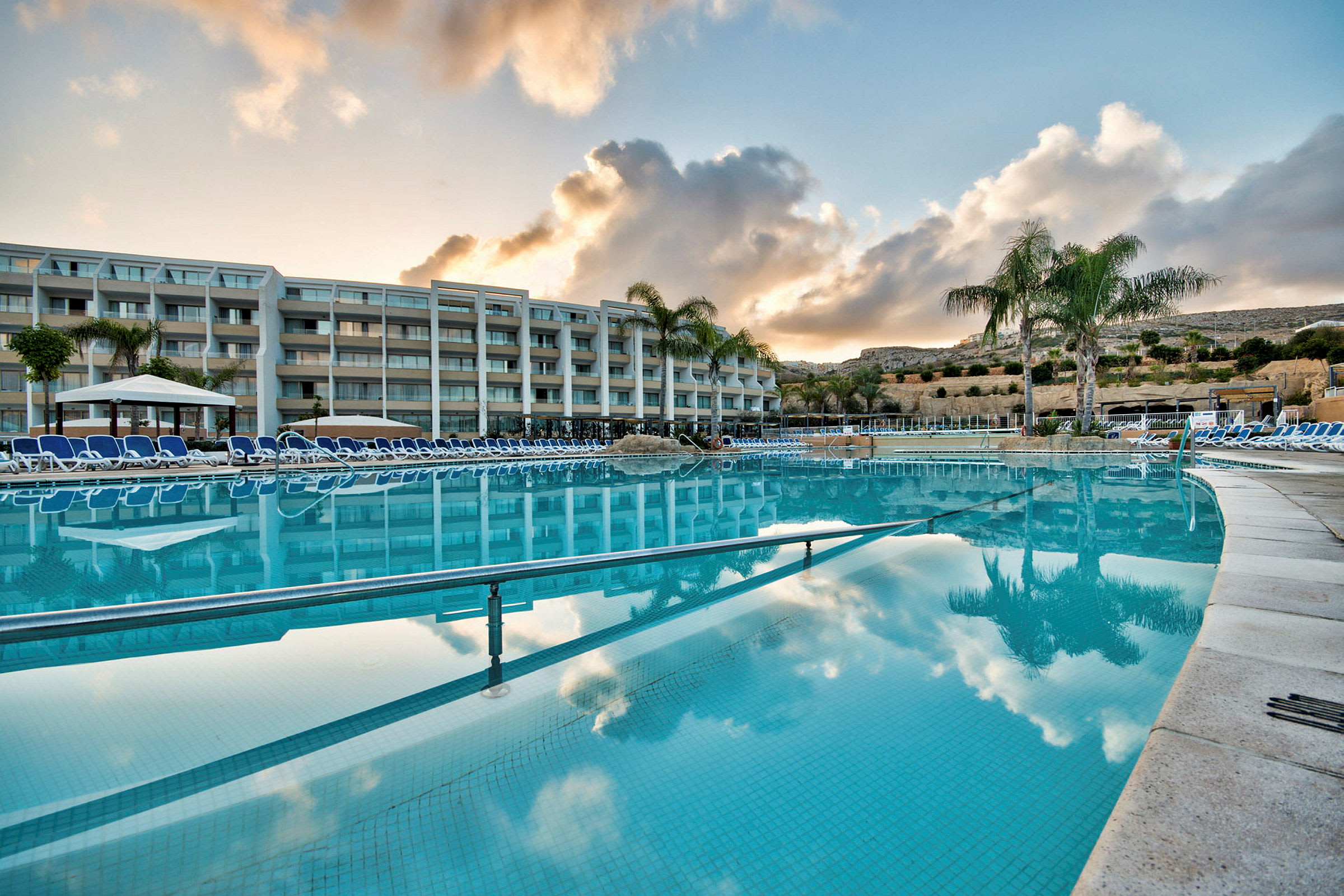 Udendørs pool med solsenge ved et hotel. (AI-genereret tekst)