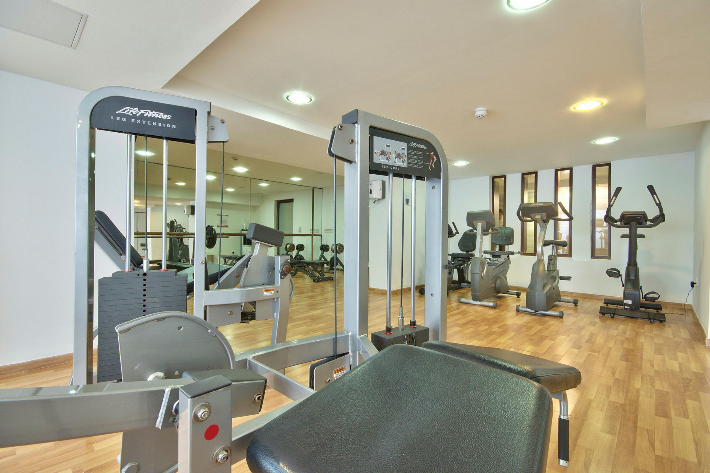 Et fitnesscenter med flere træningsmaskiner og spejlvæg. (AI-genereret tekst)