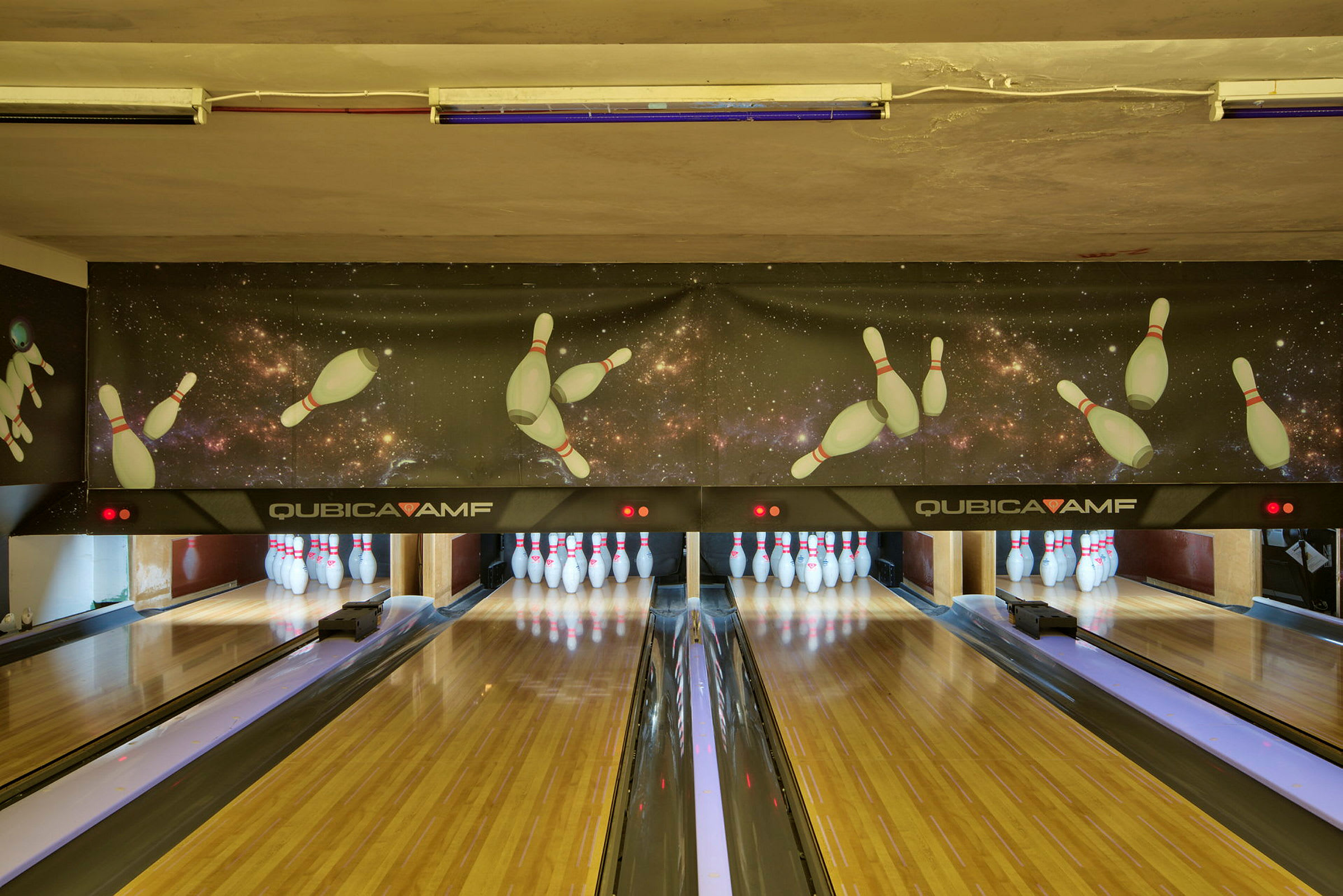 En bowlinghal med træbaner og kegler for enden af banerne. (AI-genereret tekst)