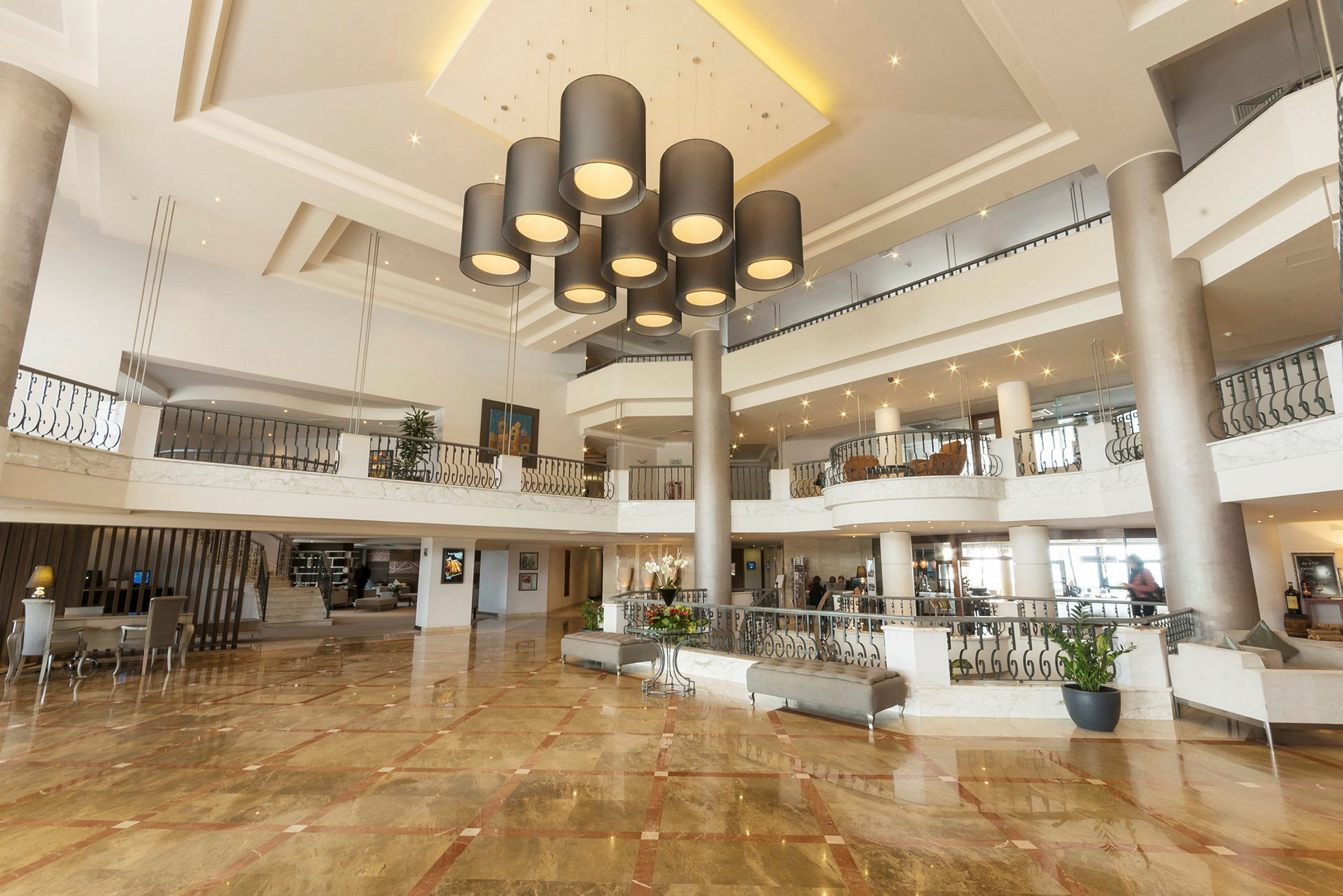 Et hotellobbyområde med elegante loftslamper, marmorgulve og moderne indretning. (AI-genereret tekst)