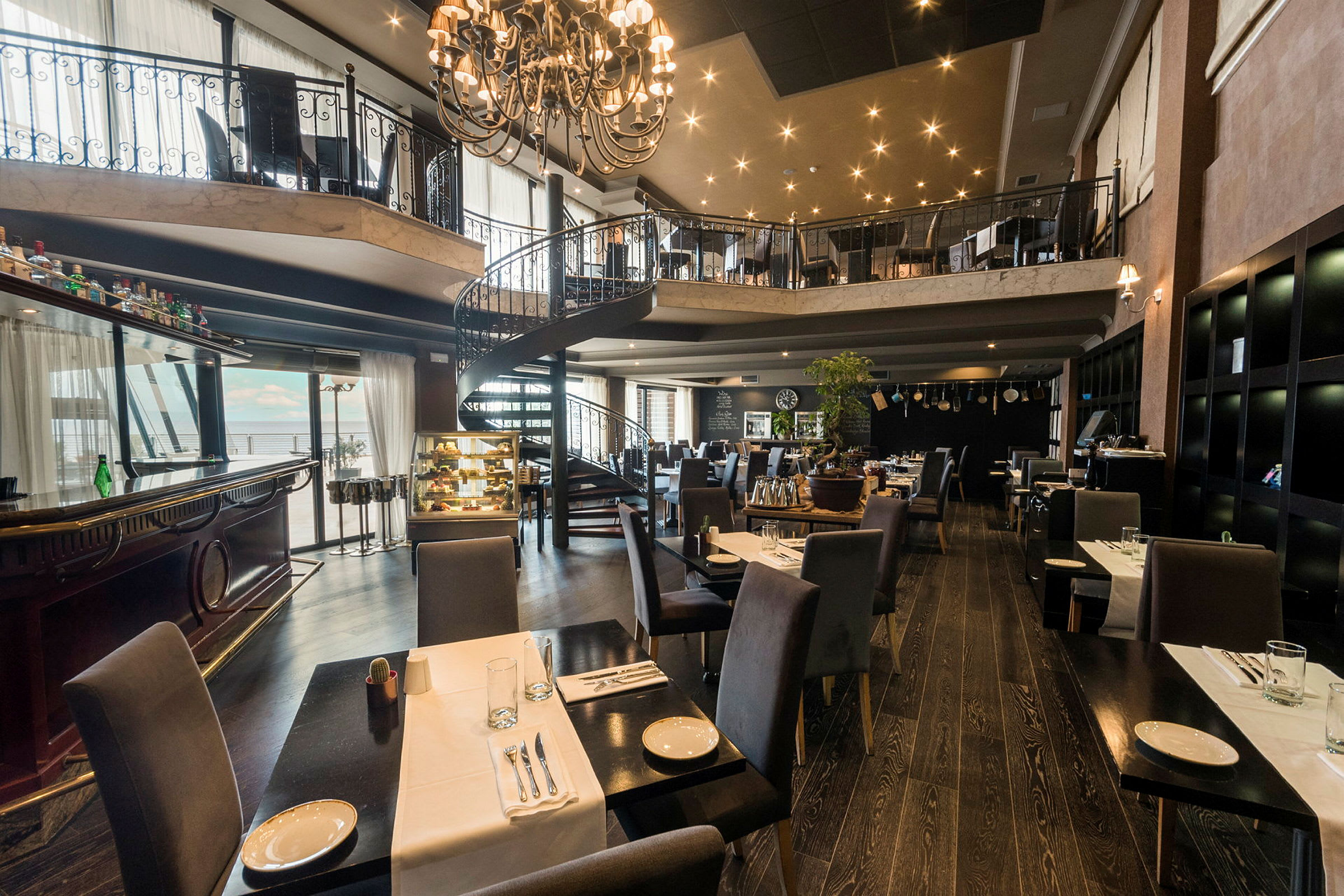 En rummelig restaurant med elegante møbler og en spiraltrappe i midten. (AI-genereret tekst)