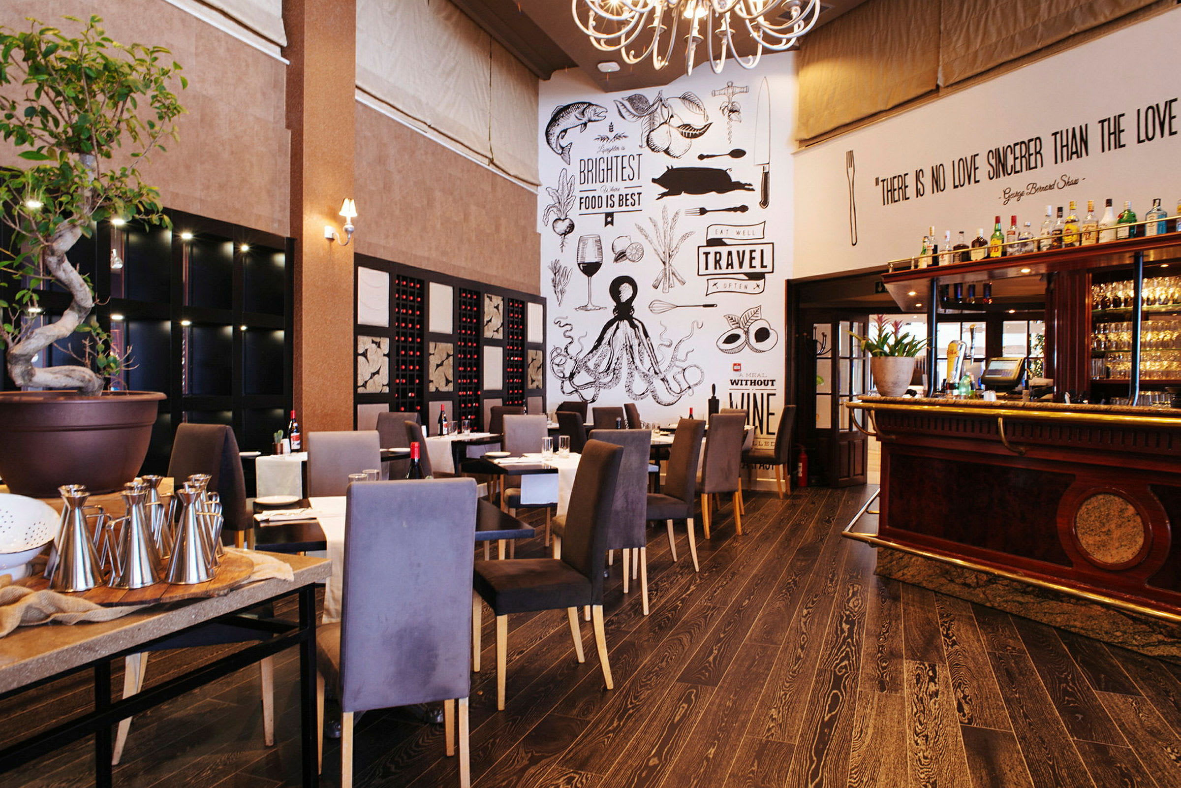 En hyggelig restaurant med siddepladser, en dekorativ væg med tekster og tegninger samt en bar til højre. (AI-genereret tekst)