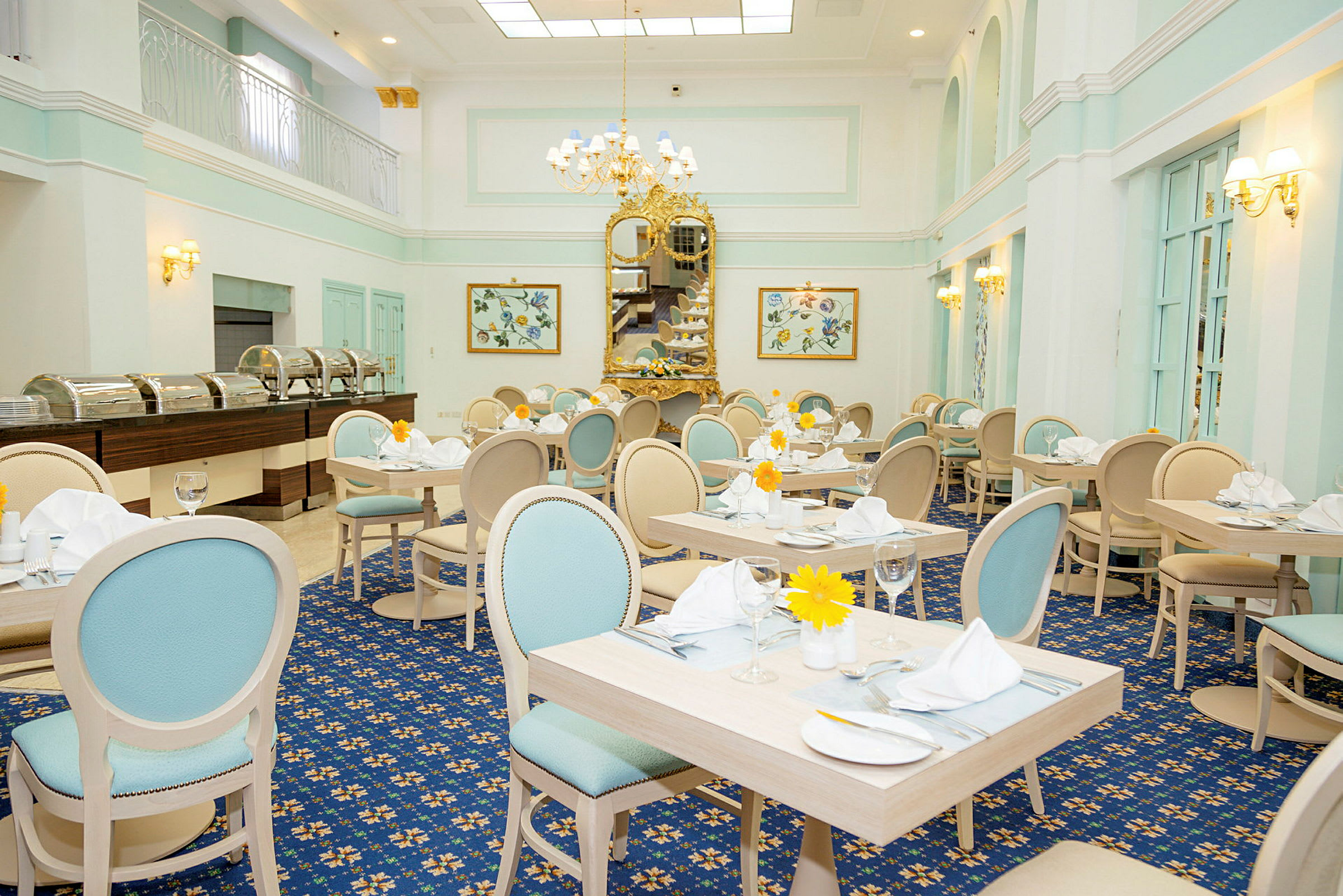 En elegant restaurant med lyse pastelfarvede møbler, dekorerede borde og et stort guldspejl, der pryder væggen. (AI-genereret tekst)